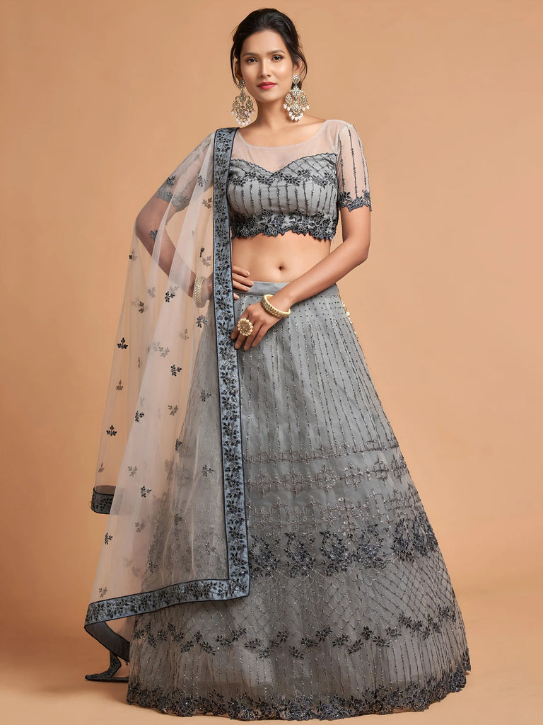 Woman wearing a grey designer lehenga choli with intricate embroidery and a matching dupatta.