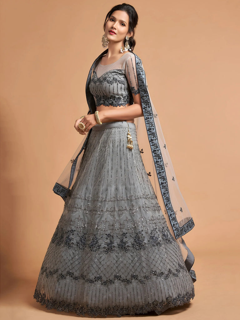 Woman wearing a grey designer lehenga choli with intricate embroidery and a sheer dupatta