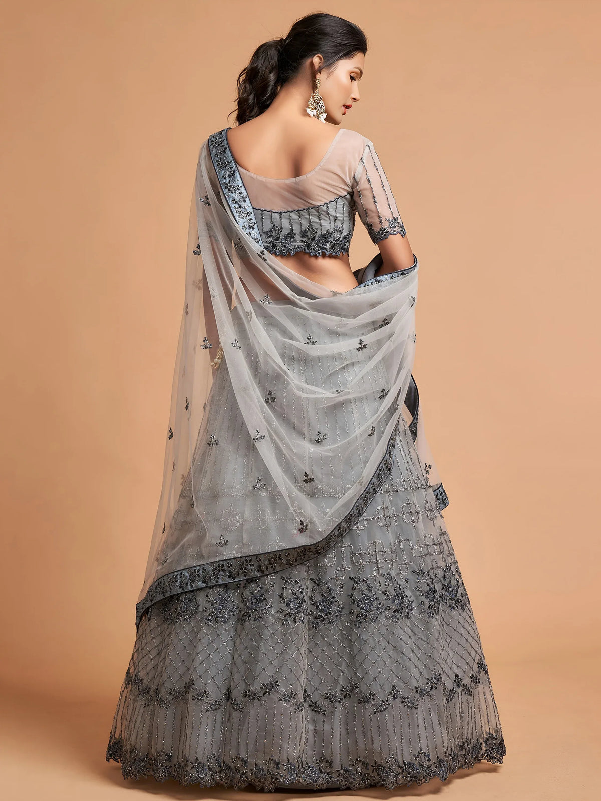 Woman in a grey embroidered designer lehenga choli with a sheer dupatta
