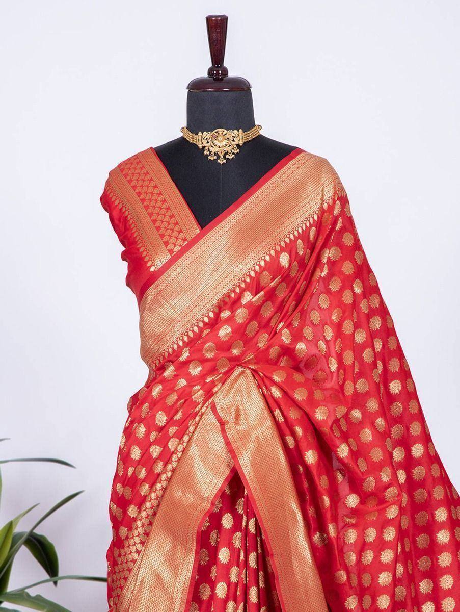 Red and gold ethnic saree with floral motifs and woven border, styled on mannequin with gold jewelry