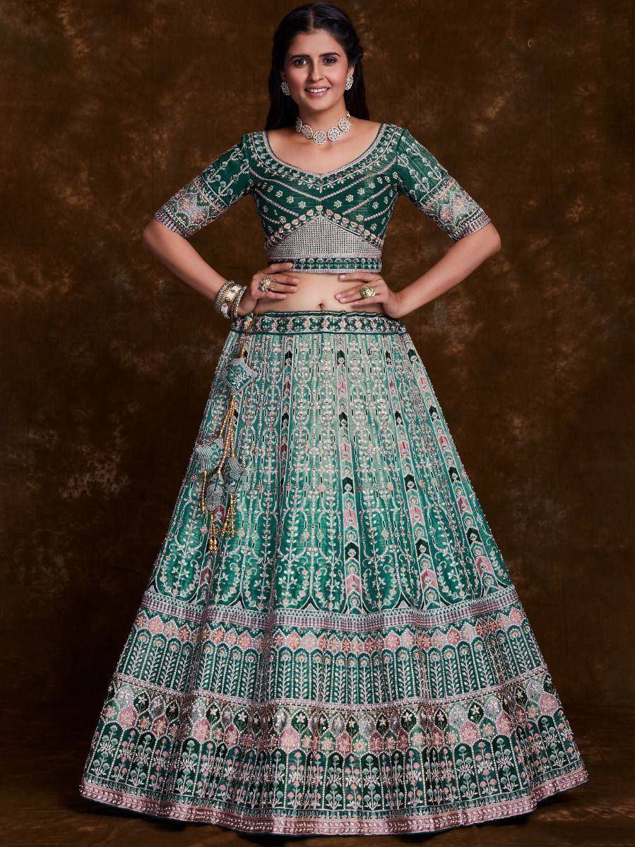 Emerald green designer lehenga choli with intricate embroidery and mirror work, perfect for weddings and festive occasions.