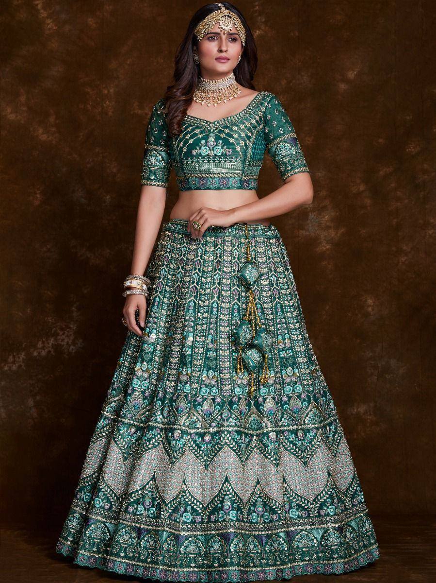 Emerald green designer lehenga choli with intricate embroidery and gold jewelry for Indian weddings
