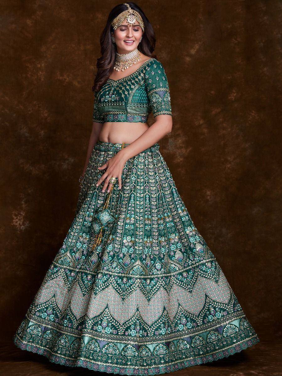 Emerald green designer lehenga choli with intricate embroidery and gold jewelry, perfect for weddings and festive occasions.