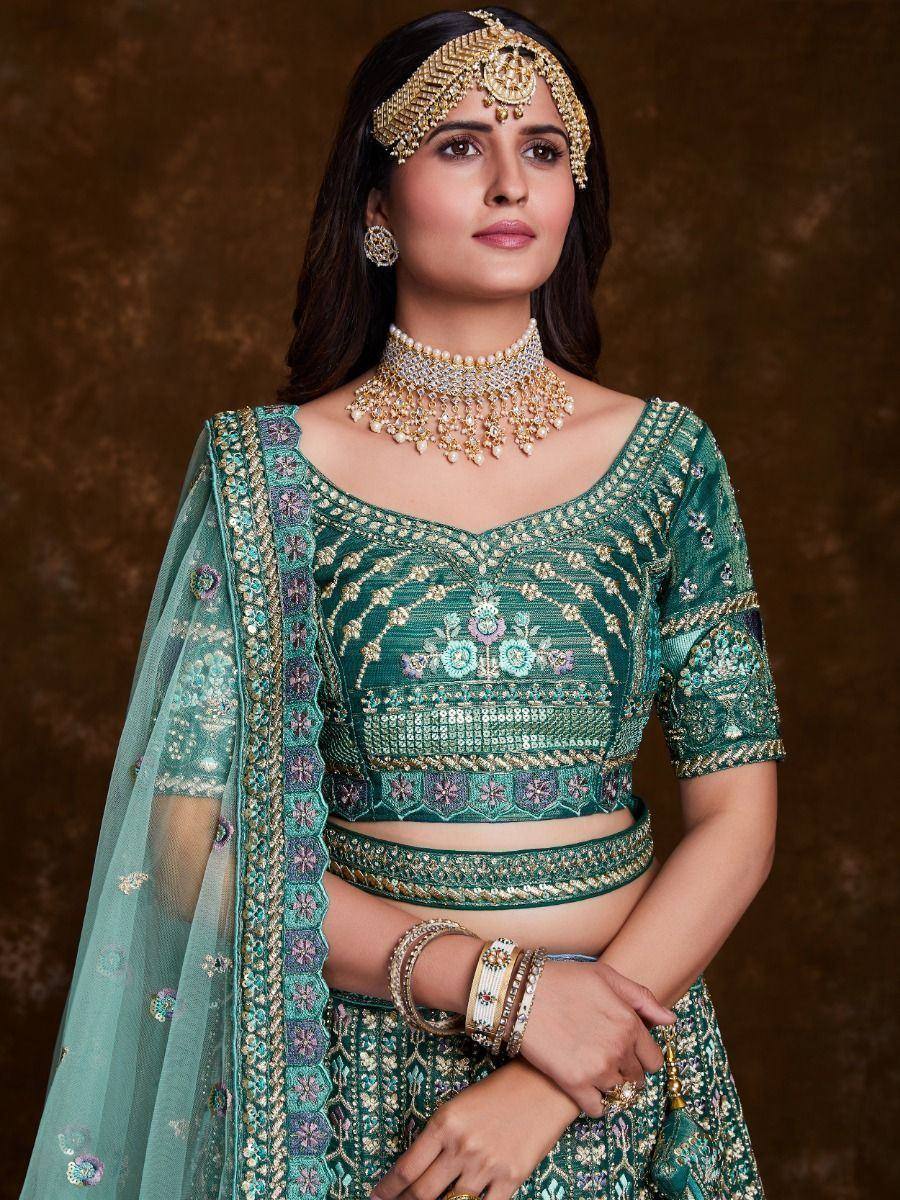 Emerald green designer lehenga choli with heavy embroidery, paired with gold jewelry and dupatta