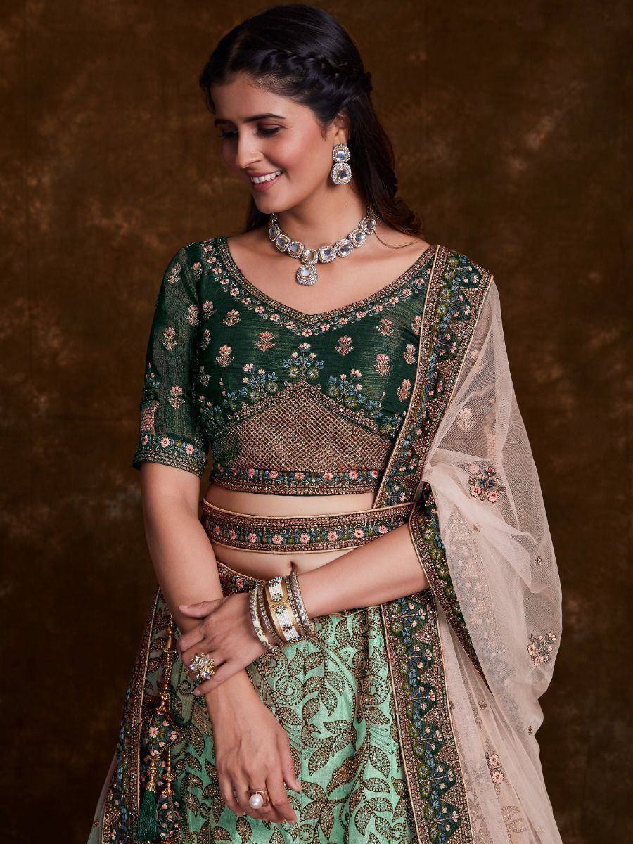 Emerald green designer lehenga choli with floral embroidery, sheer dupatta, and traditional jewelry