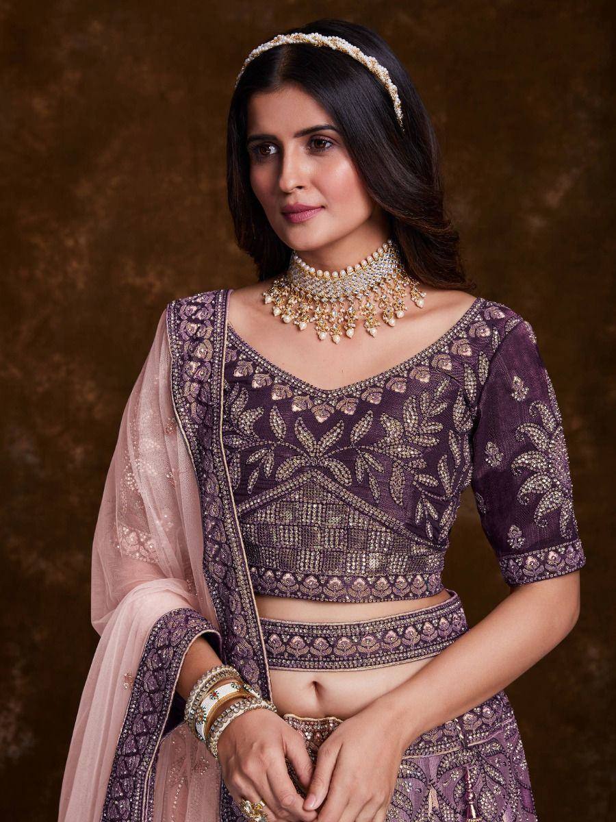 Elegant purple embroidered lehenga choli with gold detailing, paired with pink dupatta and traditional jewelry