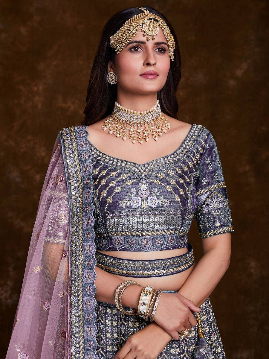 Elegant purple embroidered lehenga choli with gold jewelry and dupatta, perfect for Indian weddings and festivals.