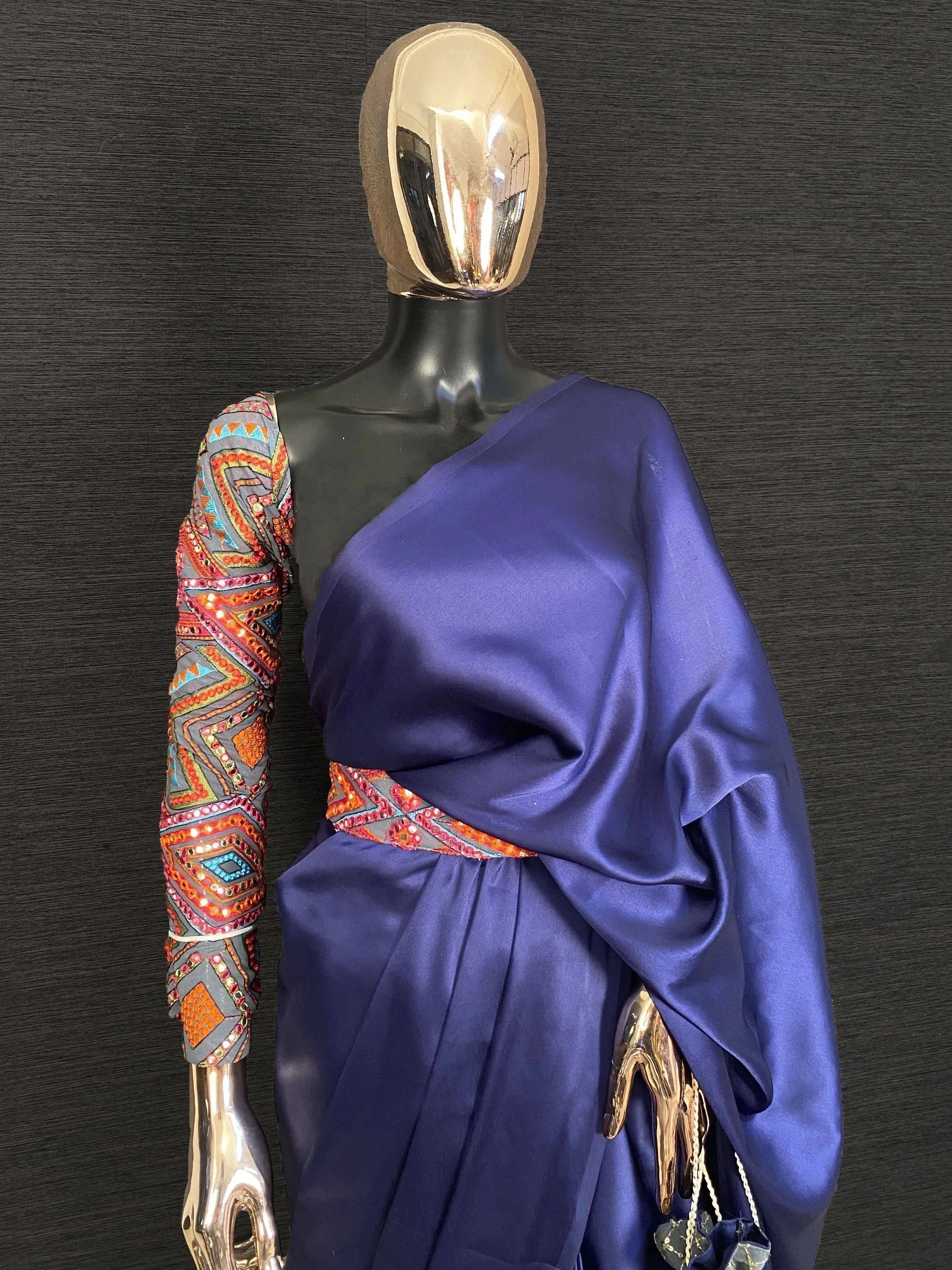 Purple one-shoulder ethnic gown with colorful embroidered sleeve and waistband, displayed on mannequin