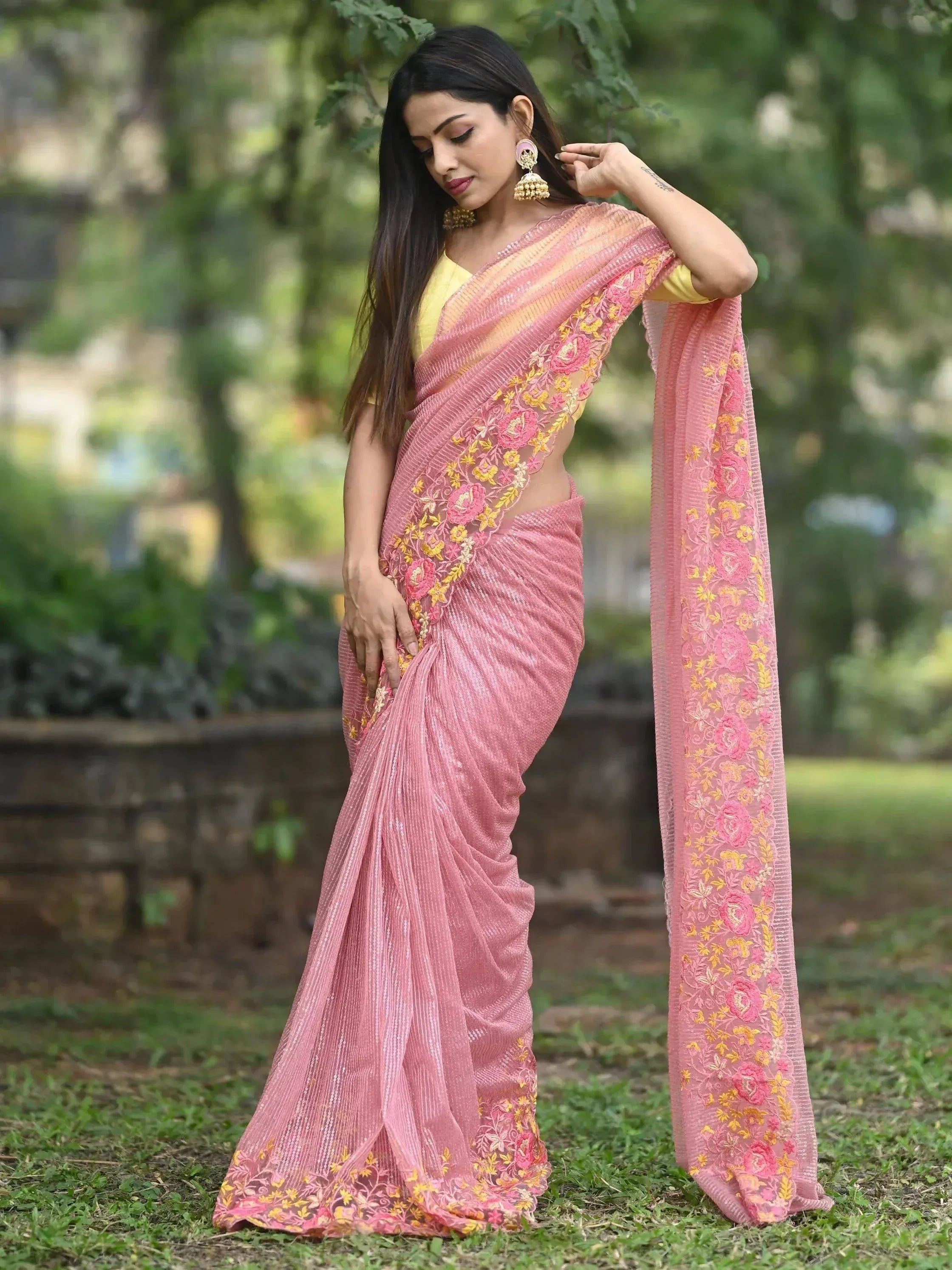 Pink embroidered saree with floral detailing, paired with yellow blouse, worn outdoors