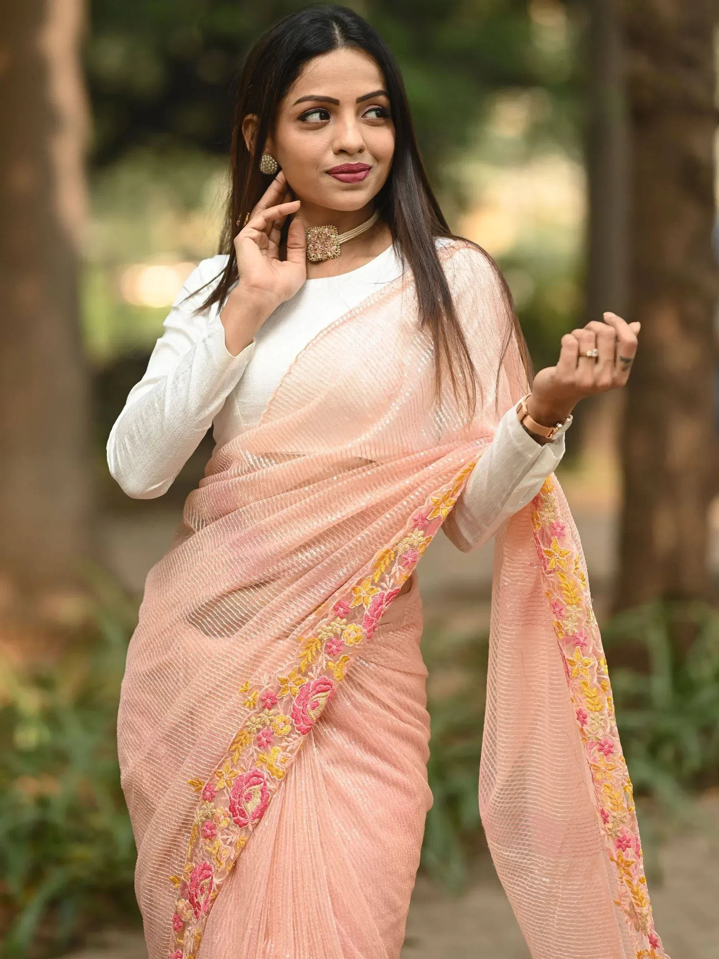 Woman in elegant pink floral embroidered saree with white blouse, perfect for Indian ethnic occasions.