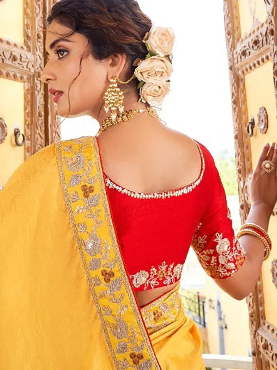 Red embroidered blouse with yellow saree, floral hair accessory, and gold jewelry for Indian ethnic wear