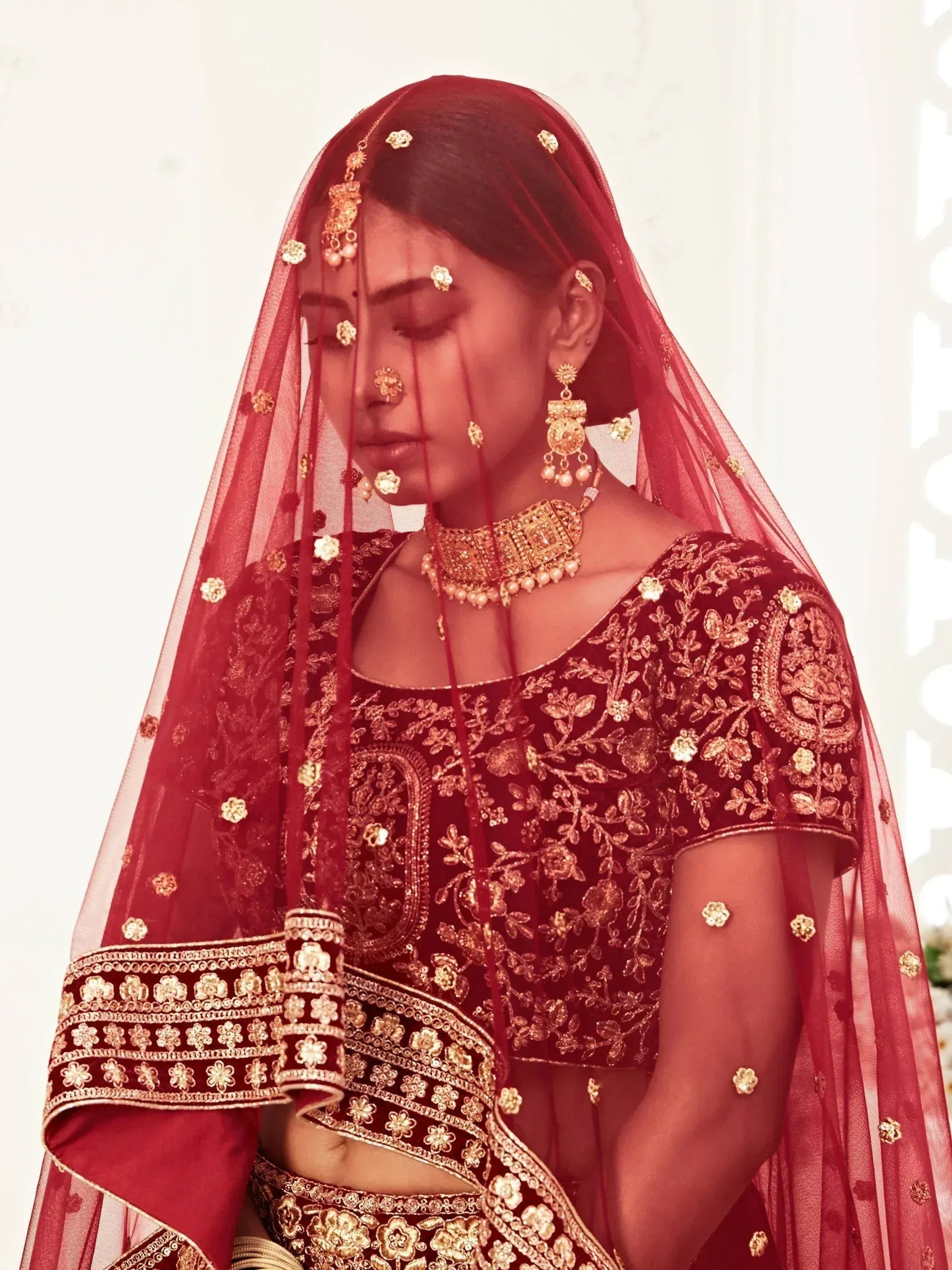 Red bridal lehenga choli with gold embroidery, dupatta, and traditional Indian jewelry for wedding