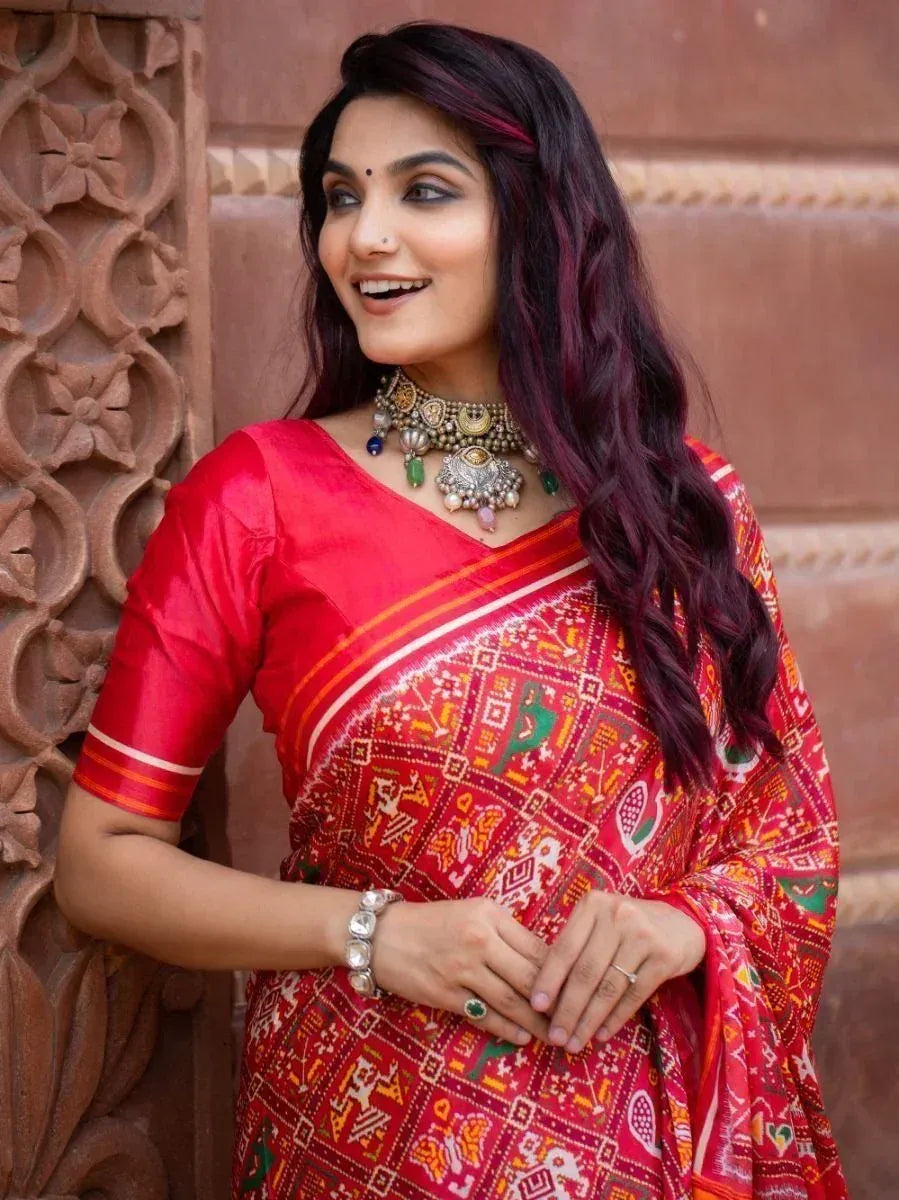 Woman in vibrant red printed saree with ethnic jewelry, perfect for Indian festive occasions