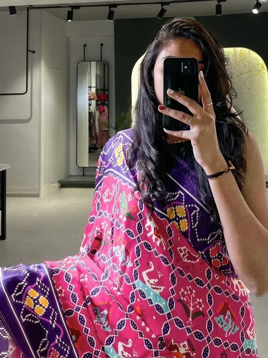Woman in vibrant pink and purple printed ethnic dress taking mirror selfie, showcasing designer Indian wear