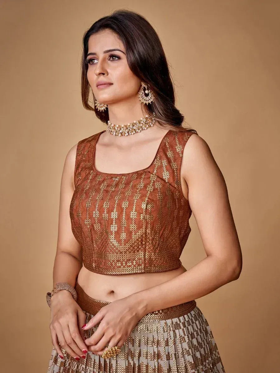 Brown and gold embroidered lehenga choli with matching jewelry, perfect for Indian ethnic wear occasions