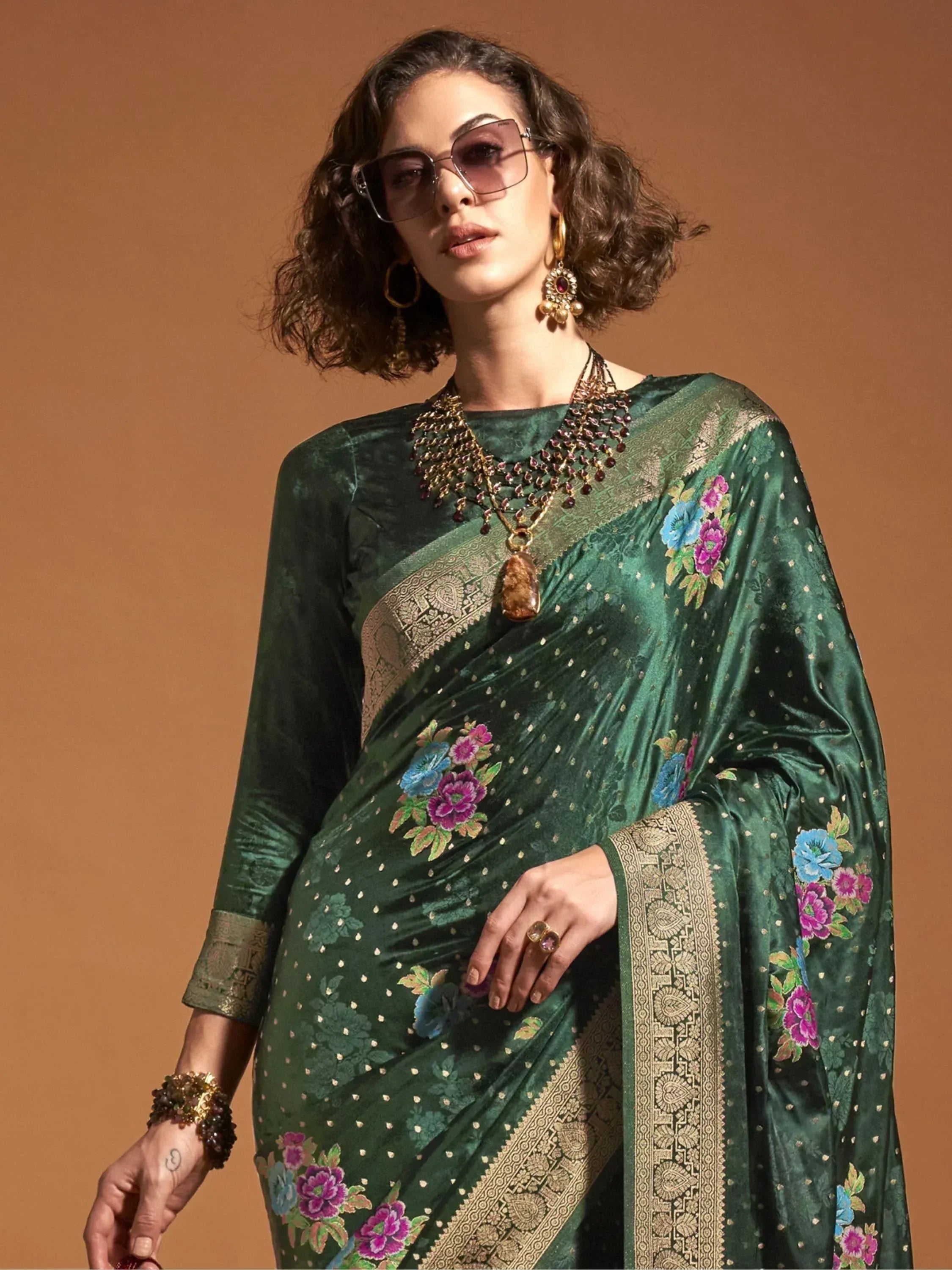 Emerald green velvet saree with floral embroidery and gold border, styled with statement jewelry