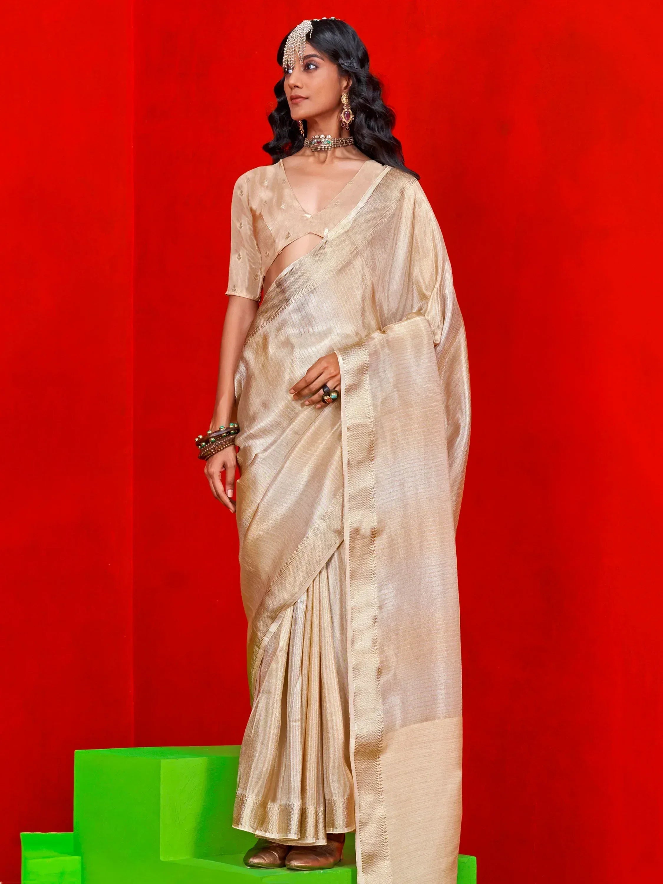 Elegant beige saree with shimmering texture, paired with matching blouse and traditional jewelry, perfect for ethnic occasions.