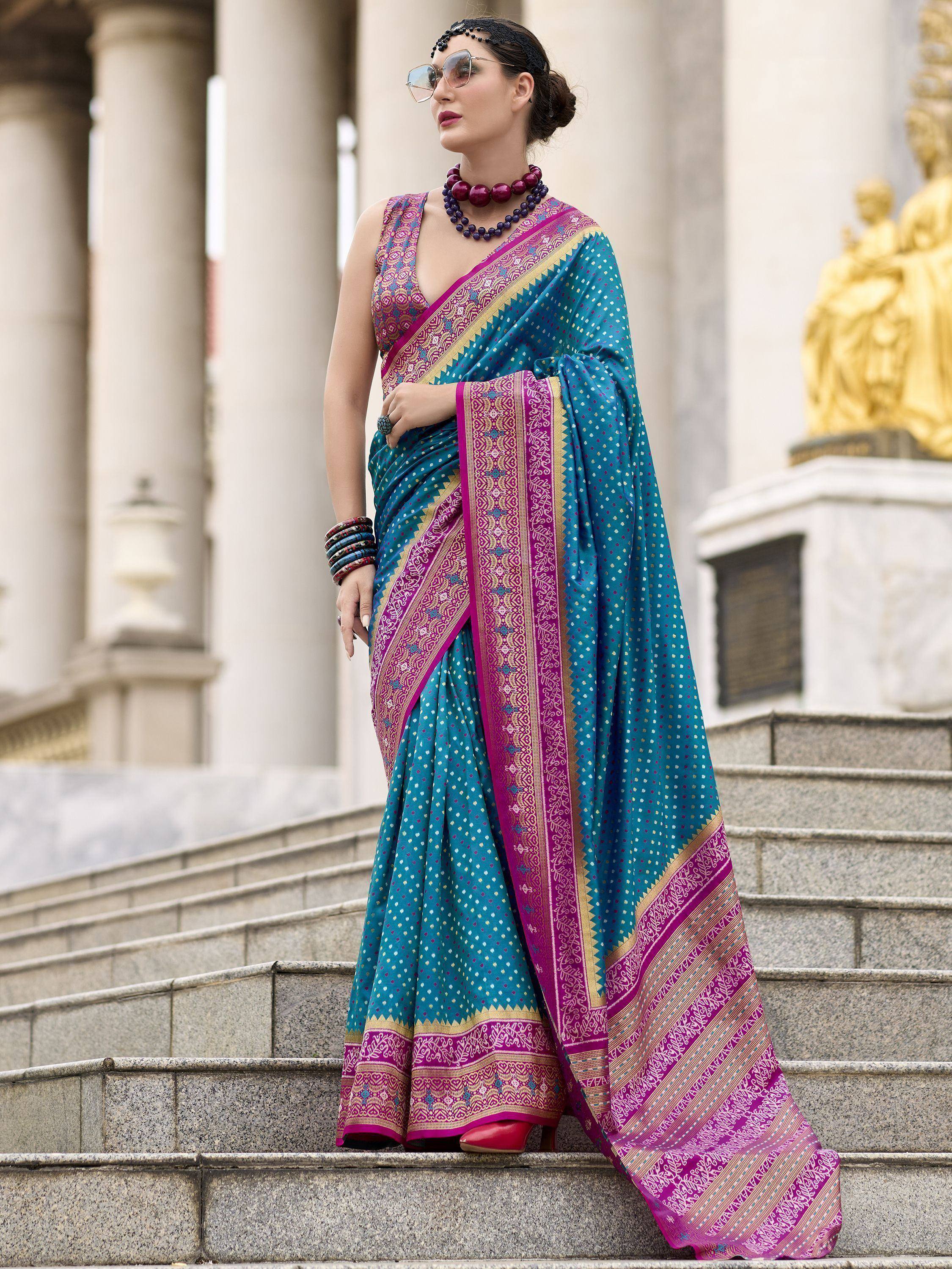Woman in teal and magenta designer saree with intricate border, styled for ethnic occasions