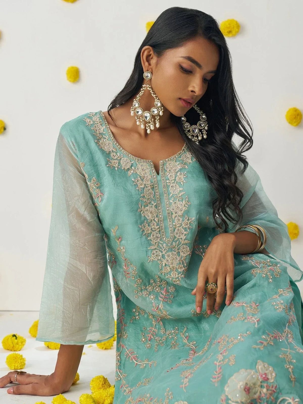 Mint green embroidered ethnic gown with gold floral detailing, paired with statement jewelry for festive occasions