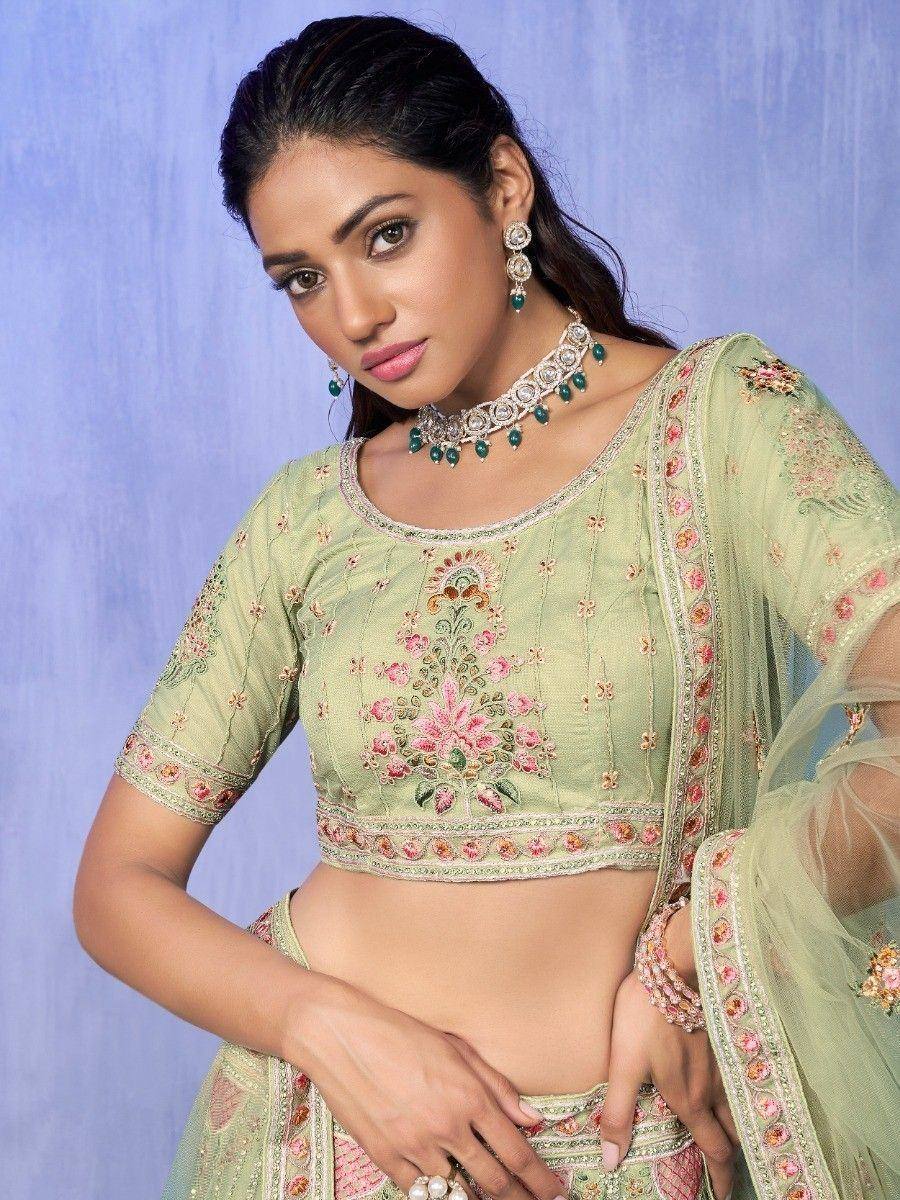 Light green embroidered lehenga choli with floral motifs and matching jewelry for Indian ethnic wear