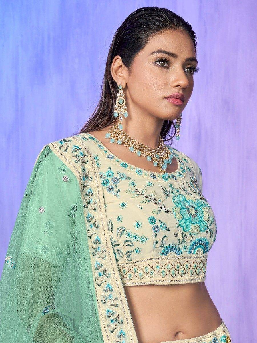 Cream and mint green embroidered lehenga choli with floral motifs and matching jewelry