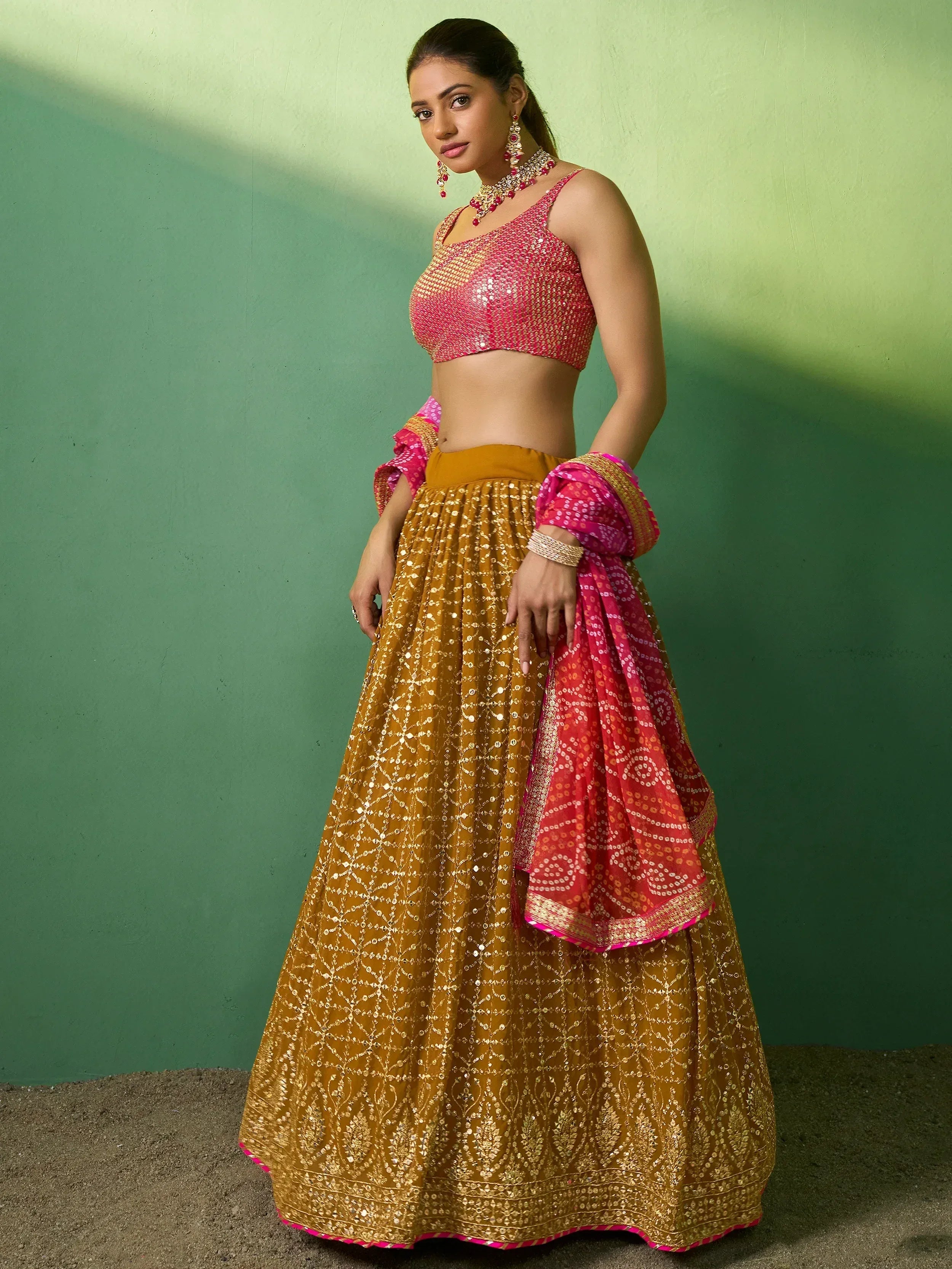 Woman in vibrant pink and gold sequined lehenga choli with matching dupatta, ethnic Indian wear
