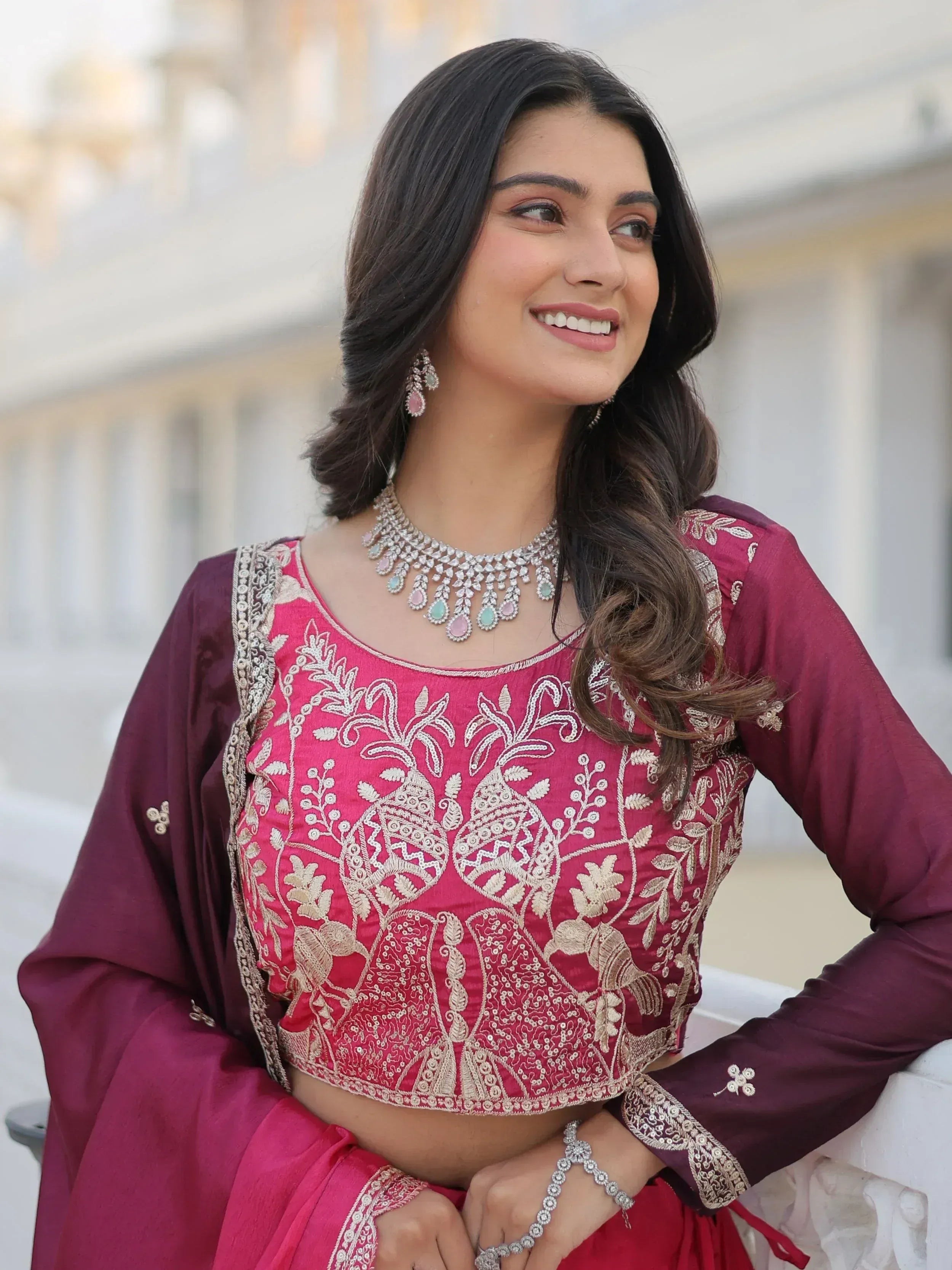 Woman in maroon embroidered lehenga choli with gold detailing and statement jewelry