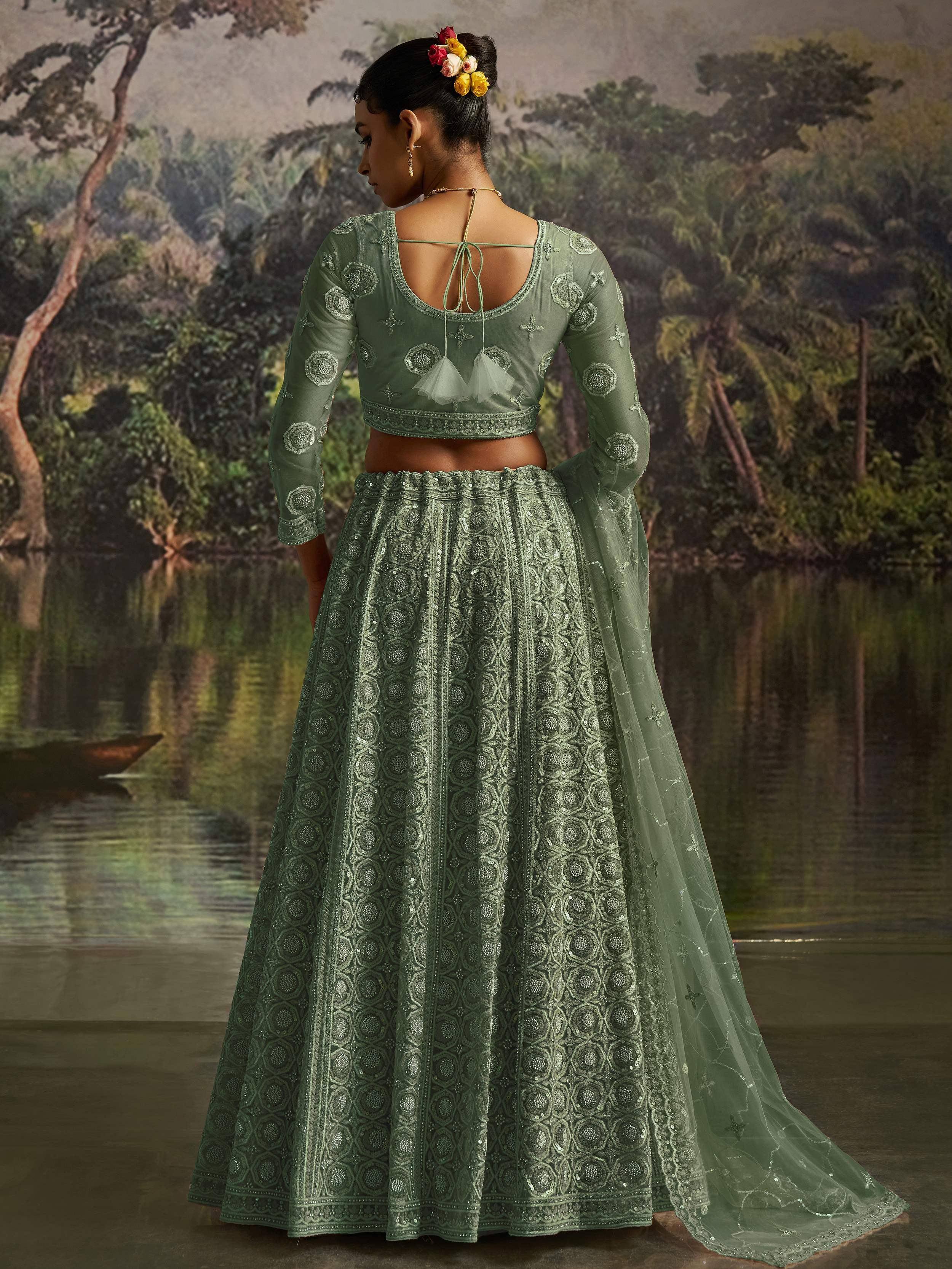 Green embroidered lehenga choli with floral hair accessory, back view near water