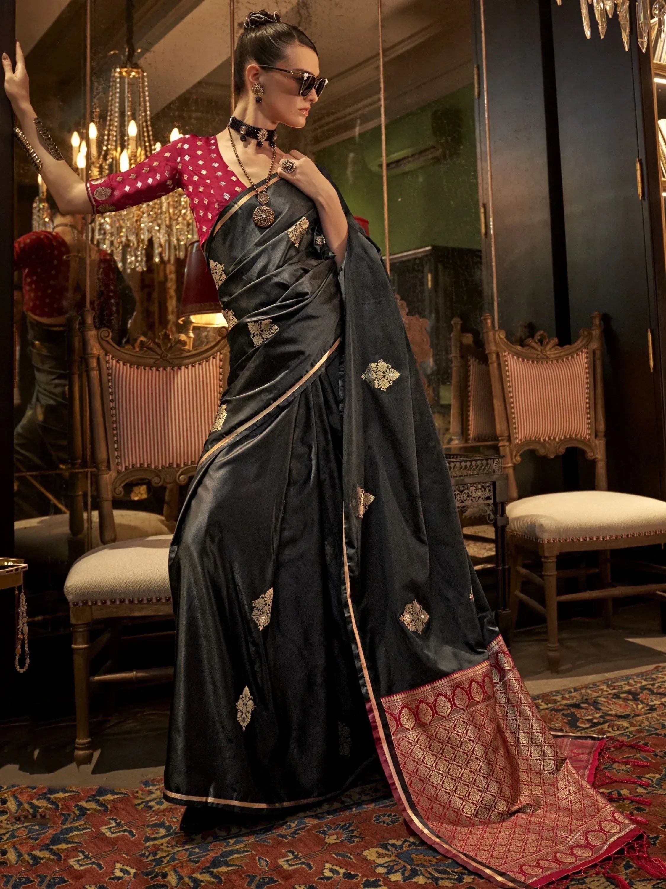 Black silk saree with gold embroidery and red border, paired with pink blouse, styled for ethnic wear