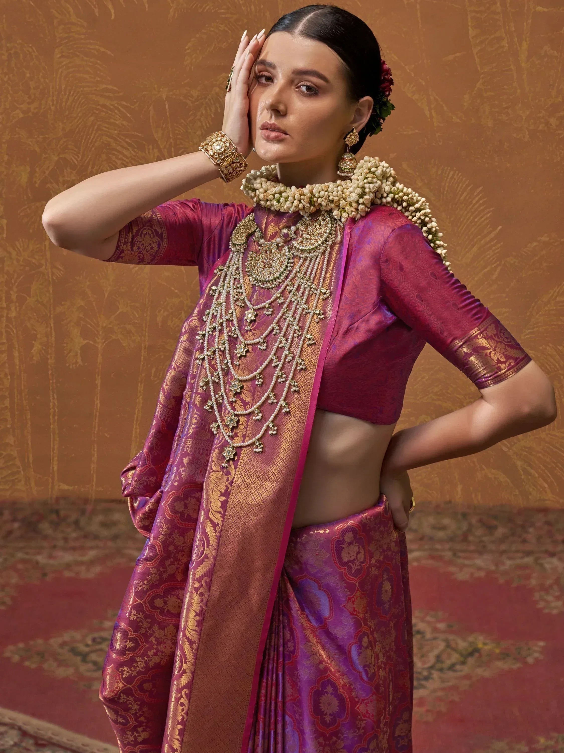 Woman in purple and gold designer saree with temple jewelry and floral garland, ethnic Indian wear