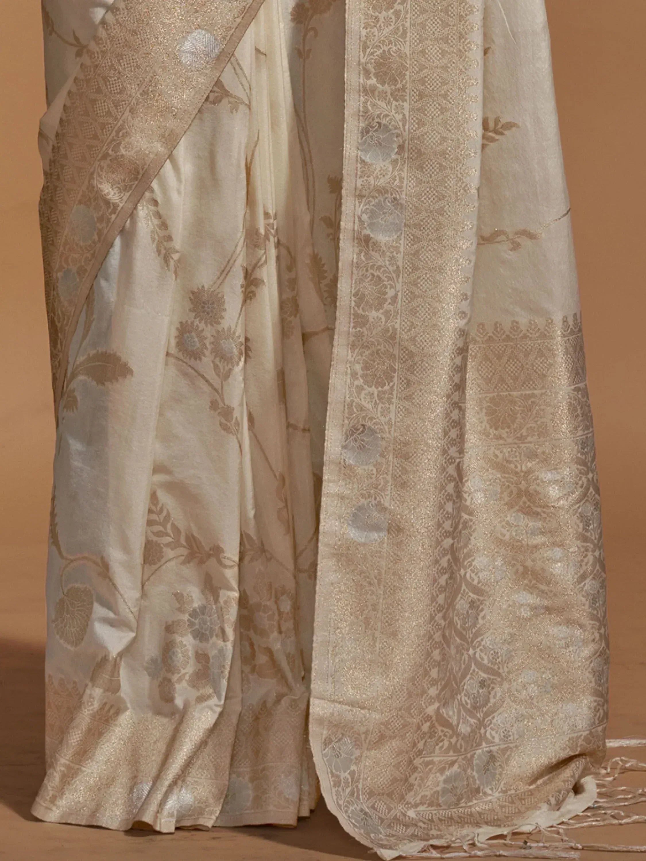 Cream floral jacquard saree with intricate gold border and woven motifs, ideal for ethnic occasions.