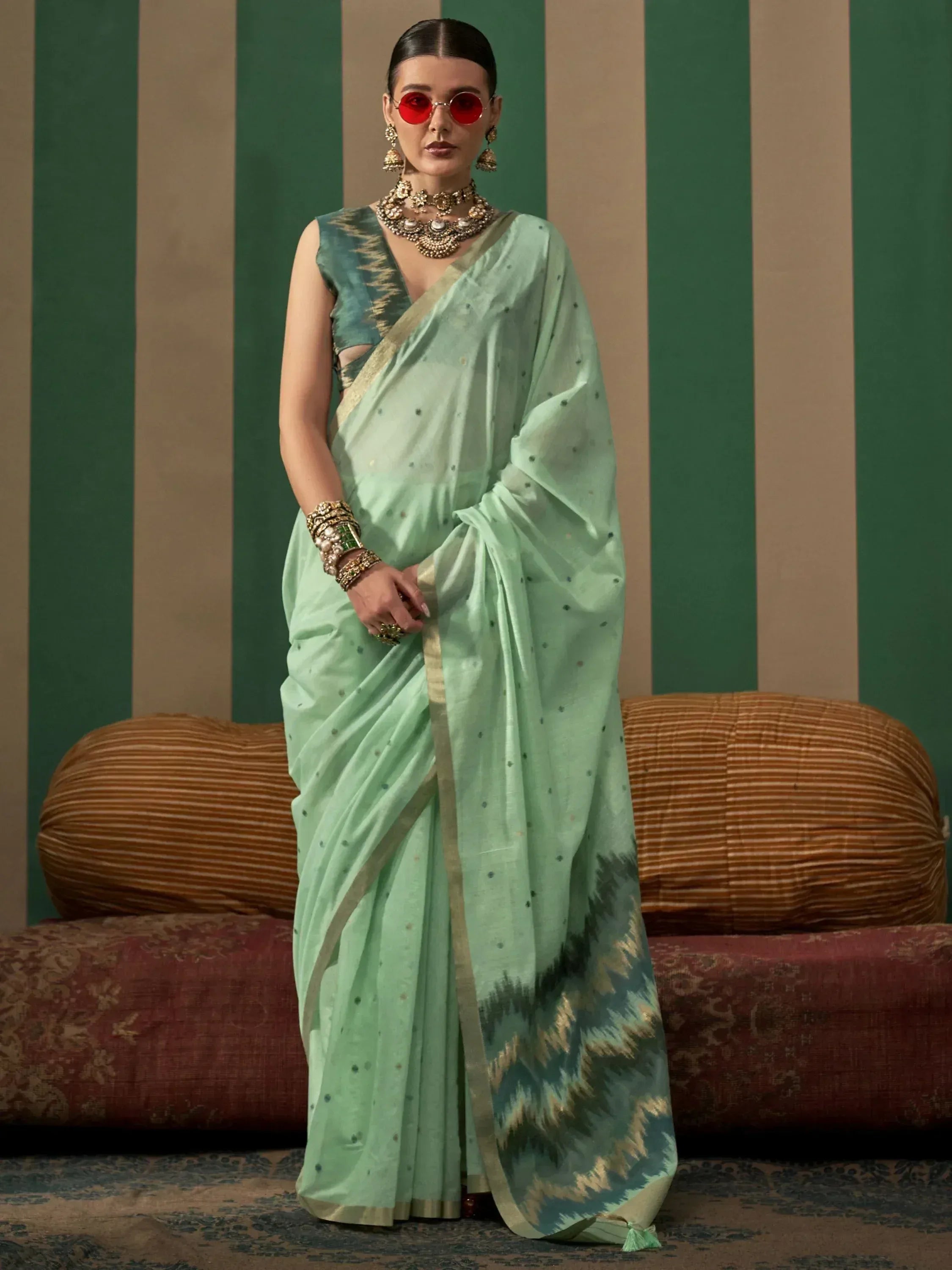 Mint green ethnic saree with ikat border, gold trim, and polka dots, styled with traditional jewelry for Indian occasions