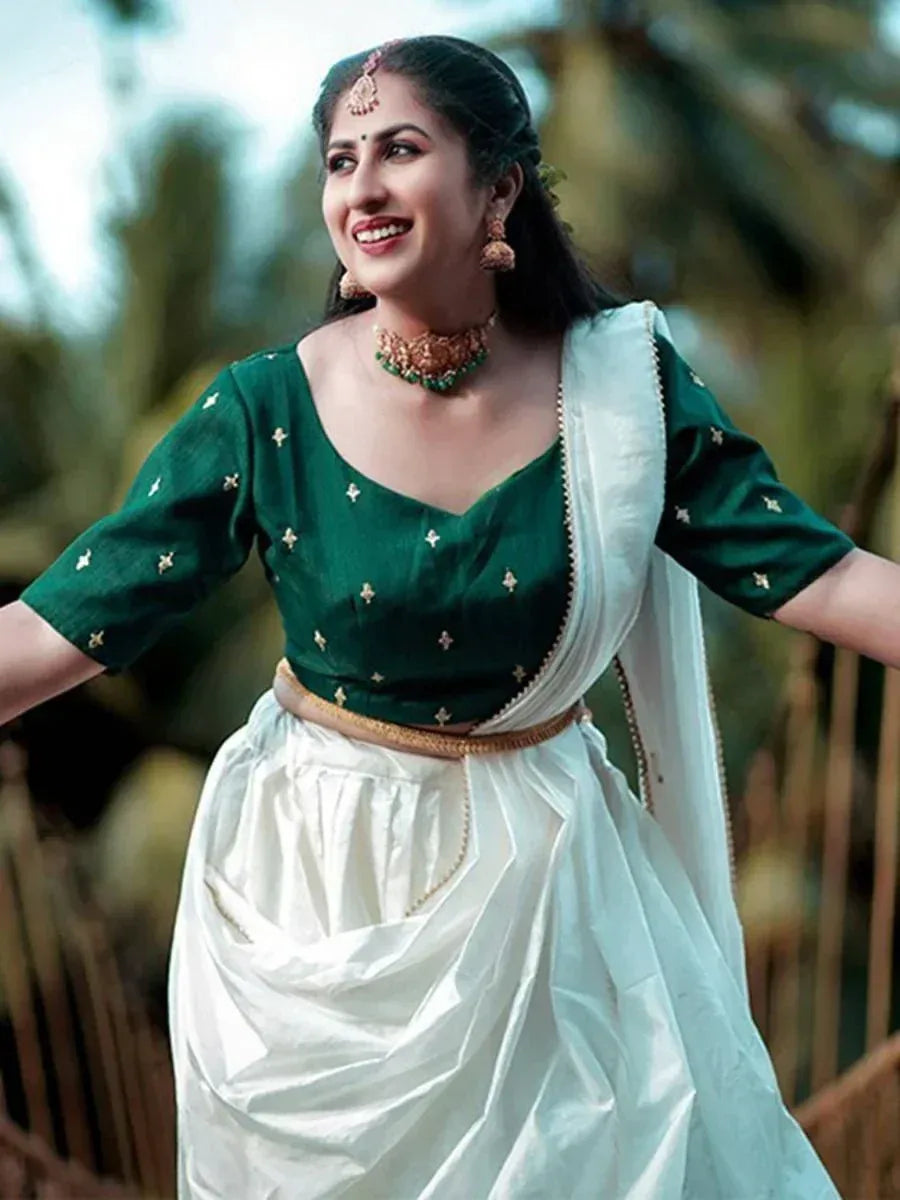 Woman in green embroidered blouse with white drape, traditional Indian ethnic wear