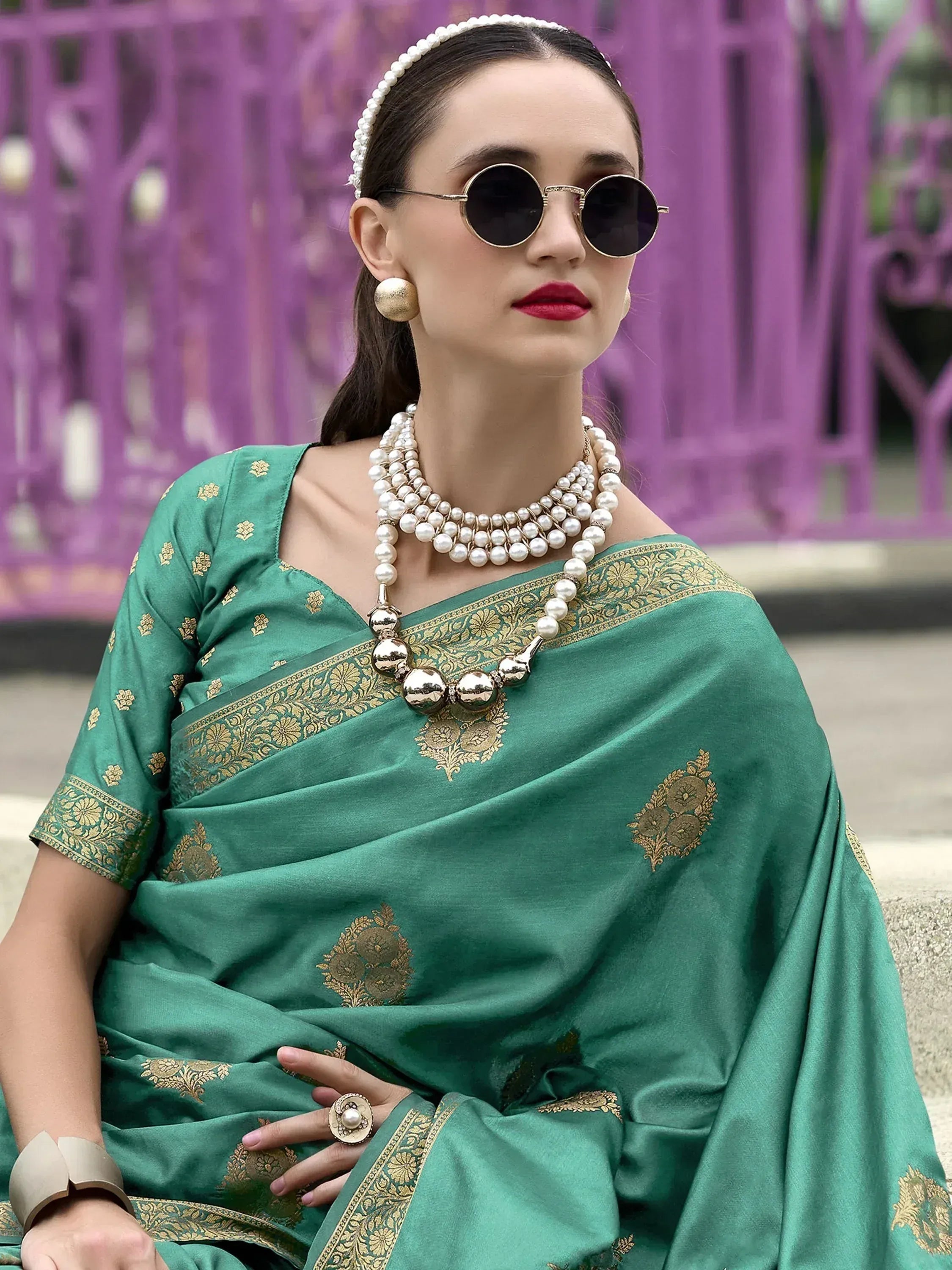 Green silk saree with gold embroidery, pearl jewelry, and round sunglasses for ethnic wear