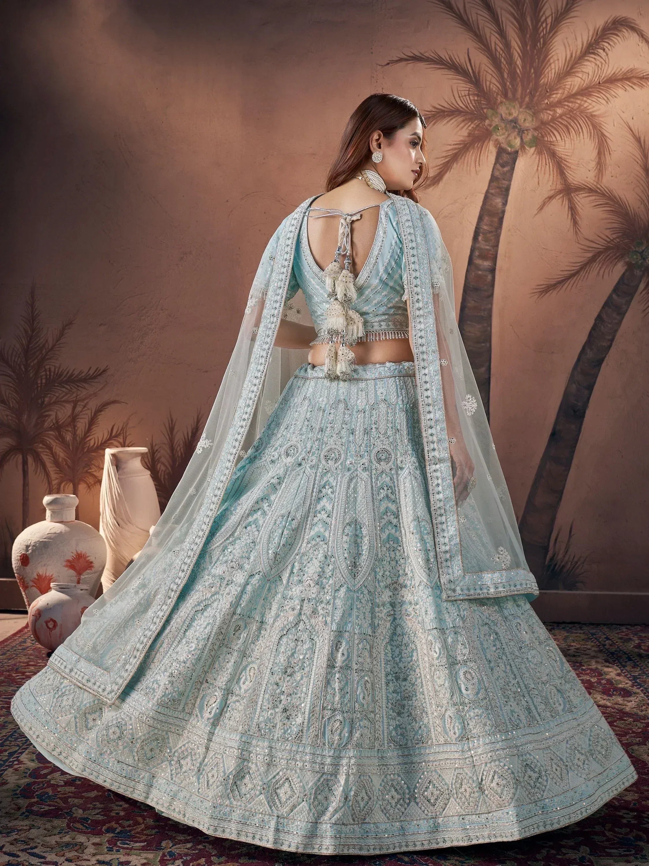 Light blue designer lehenga choli with intricate embroidery and tassels, perfect for Indian weddings or festive occasions.