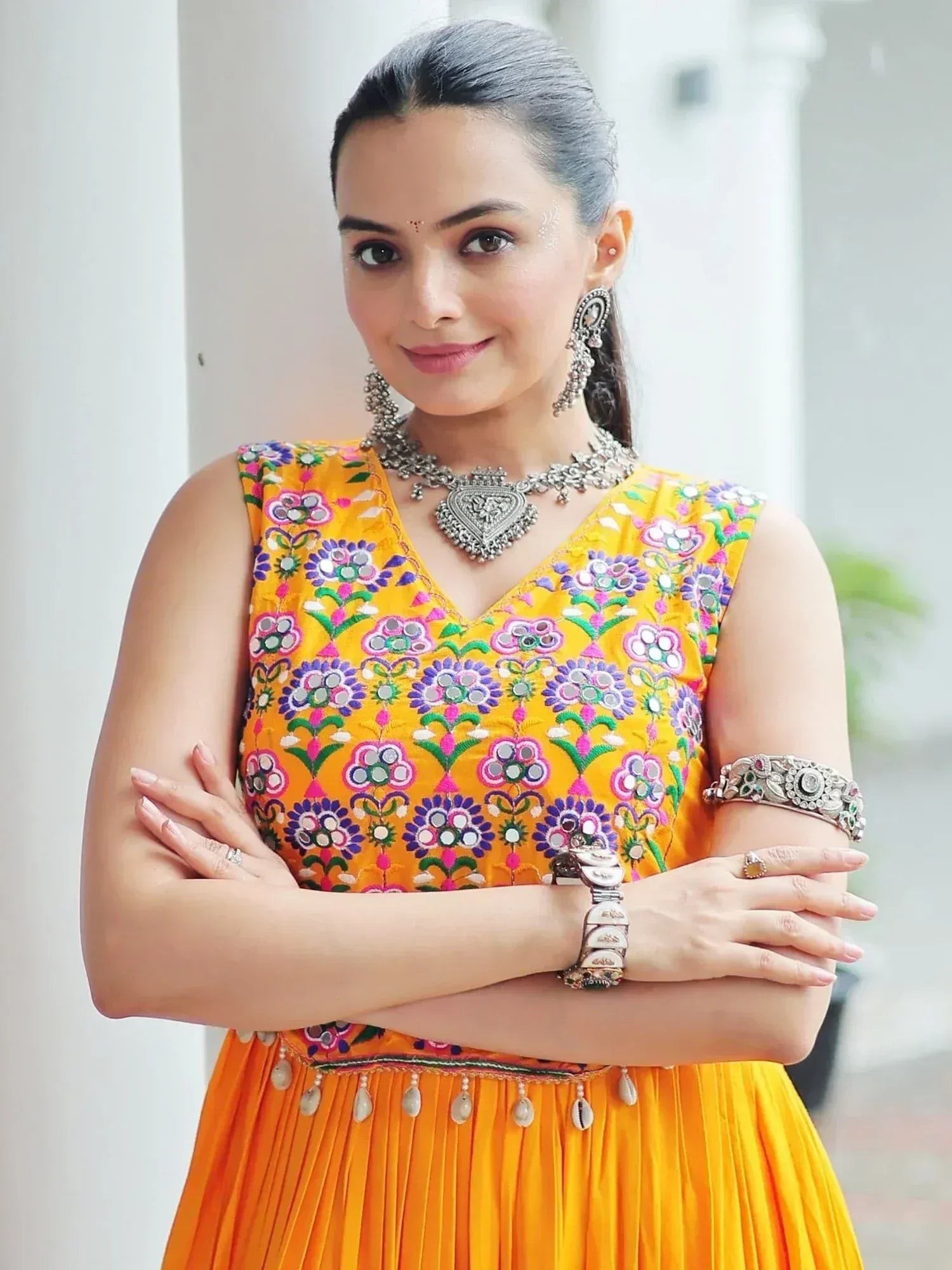 Woman in vibrant yellow floral embroidered ethnic gown with mirror work, paired with traditional silver jewelry