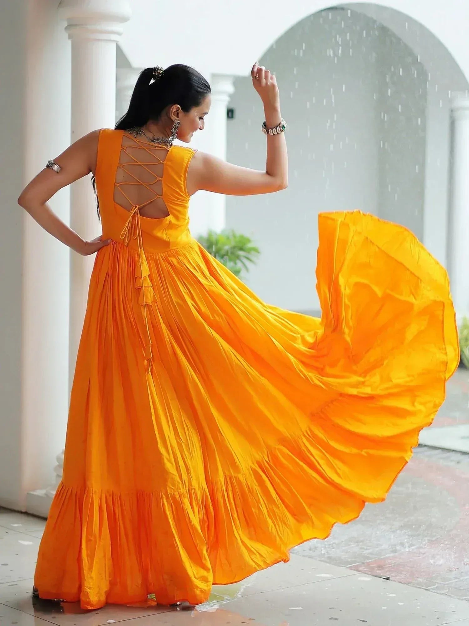 Vibrant orange ethnic gown with crisscross back, flowing skirt, perfect for festive occasions and weddings.