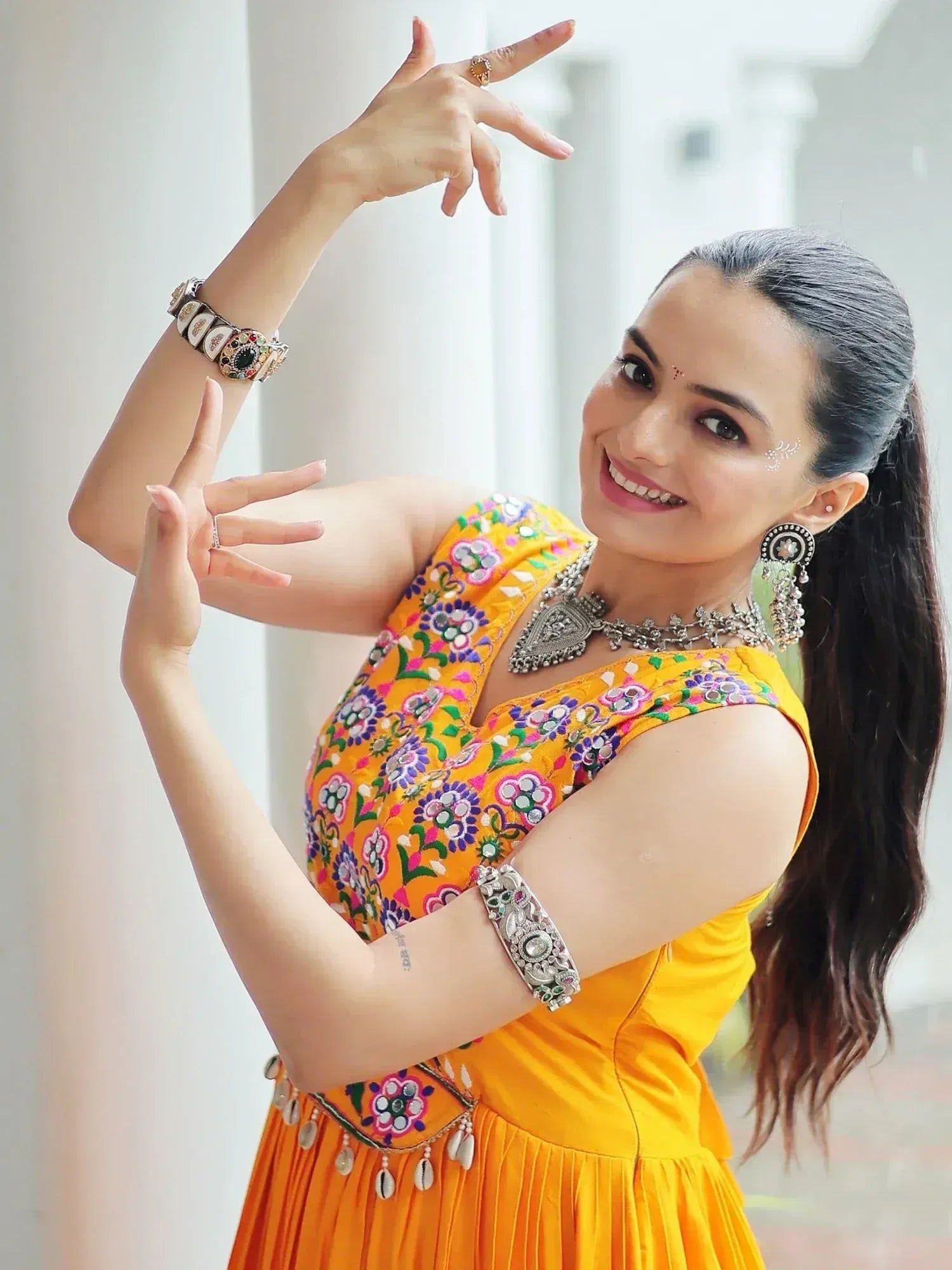 Woman in vibrant yellow embroidered ethnic gown with traditional jewelry, perfect for festive occasions.