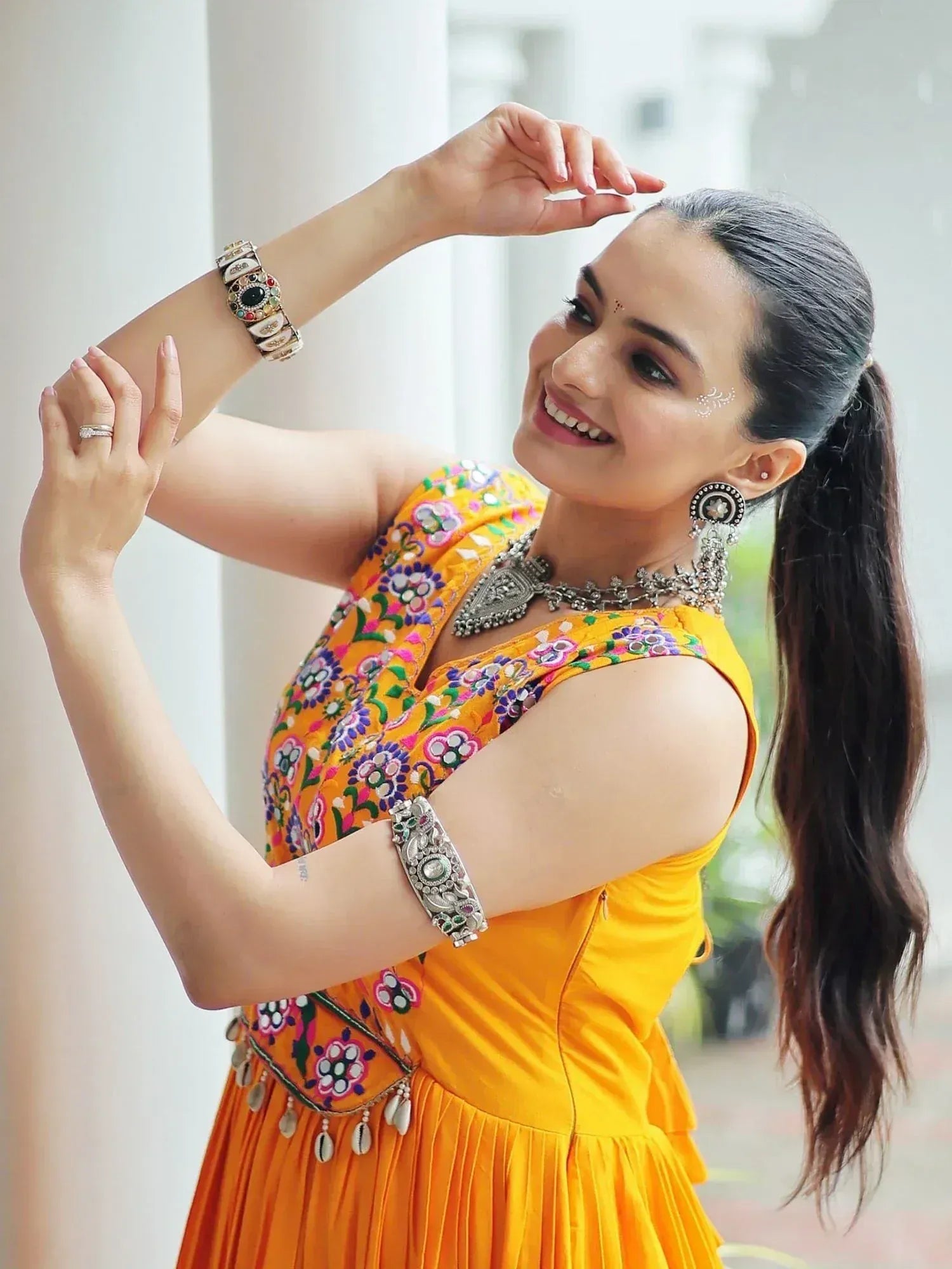 Woman in vibrant yellow embroidered ethnic gown with traditional jewelry, perfect for festive occasions.