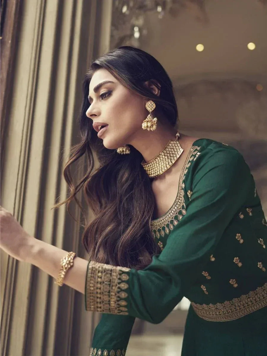 Elegant green designer salwar kameez with gold embroidery, paired with traditional jewelry for festive occasions.
