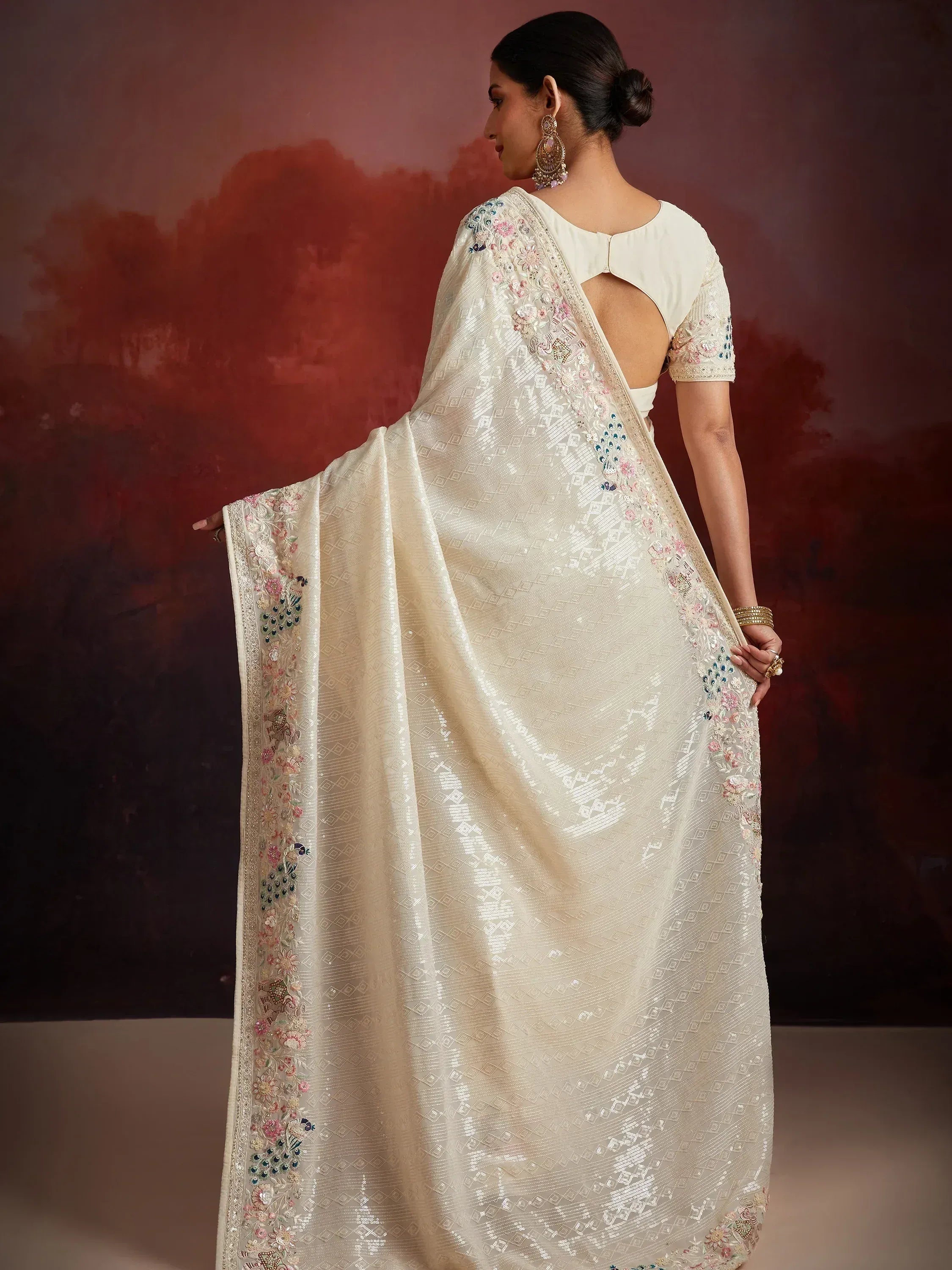 Elegant ivory saree with peacock embroidery and sequin work, paired with backless blouse for Indian ethnic wear