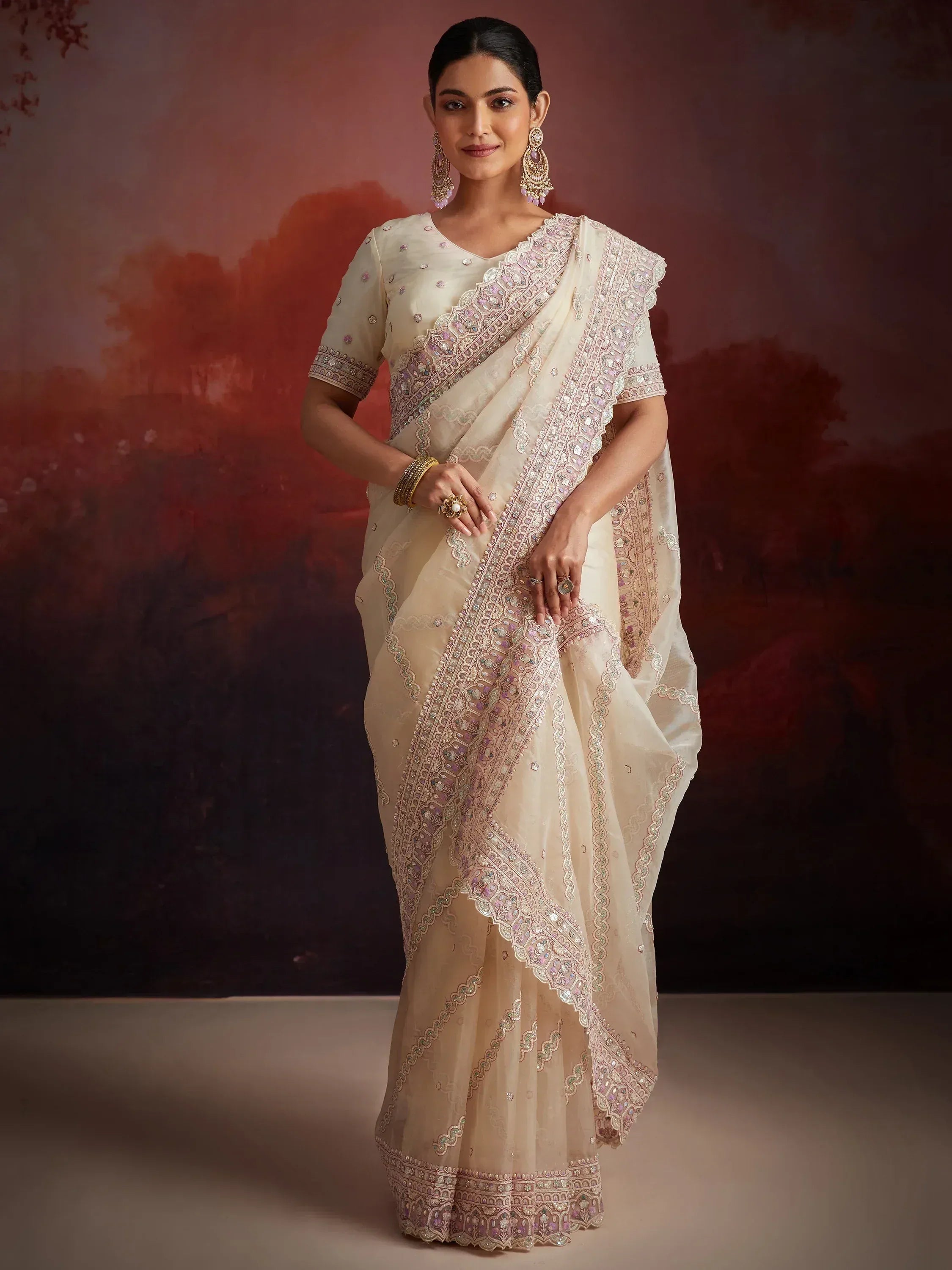 Elegant cream saree with intricate pink and gold embroidery, perfect for Indian ethnic occasions.