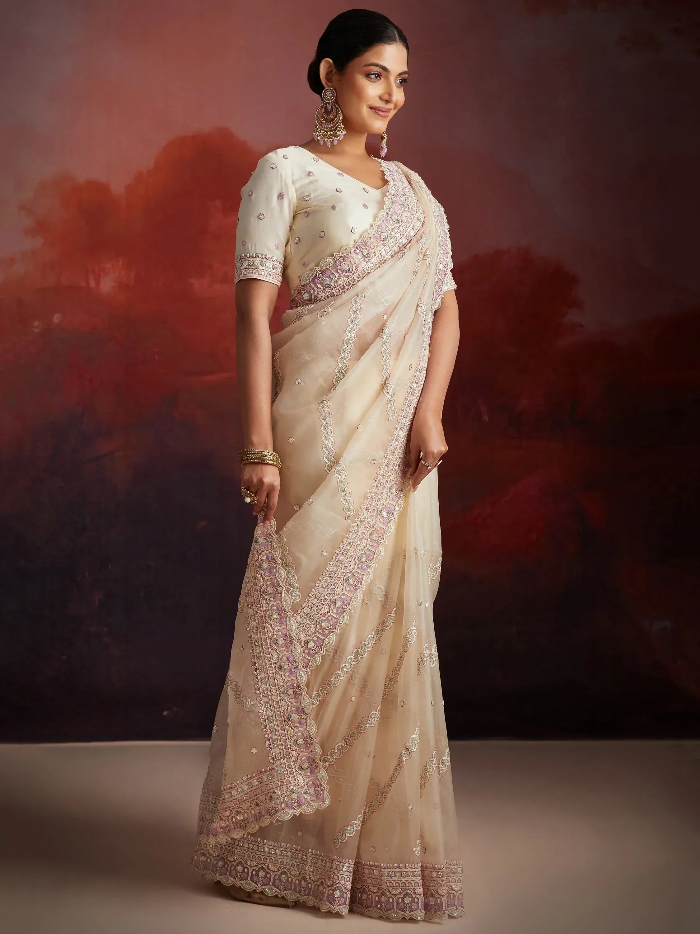Elegant cream saree with intricate pink and gold embroidery, perfect for Indian ethnic occasions.
