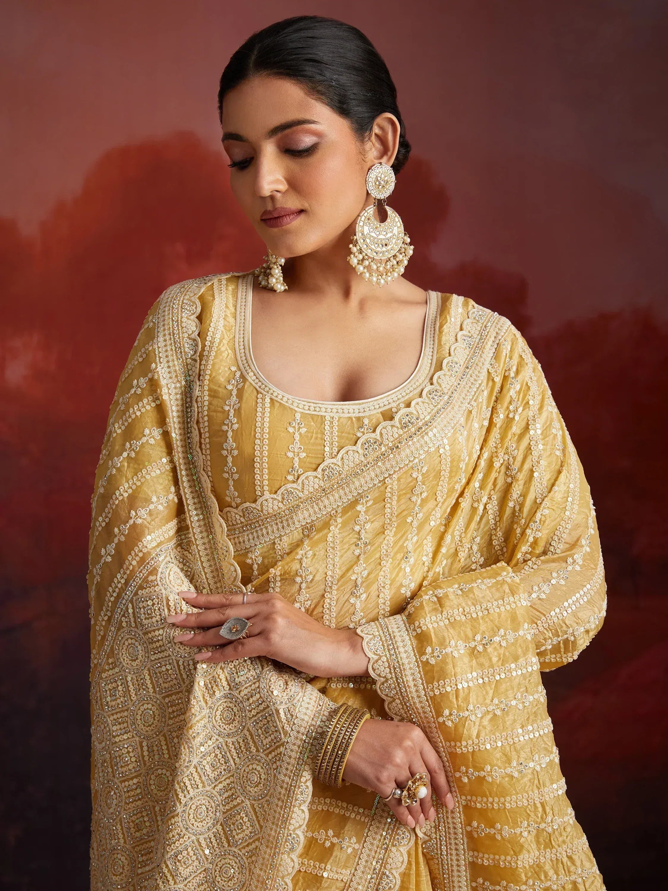 Elegant yellow embroidered salwar kameez with pearl jewelry, perfect for Indian ethnic occasions.