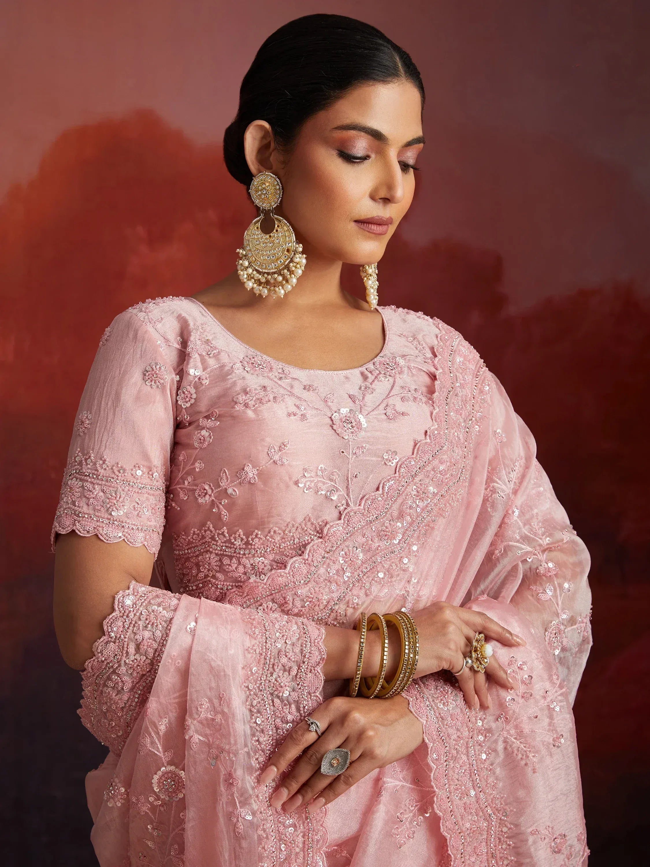 Pink embroidered salwar kameez with floral sequin work, paired with statement gold earrings and bangles.