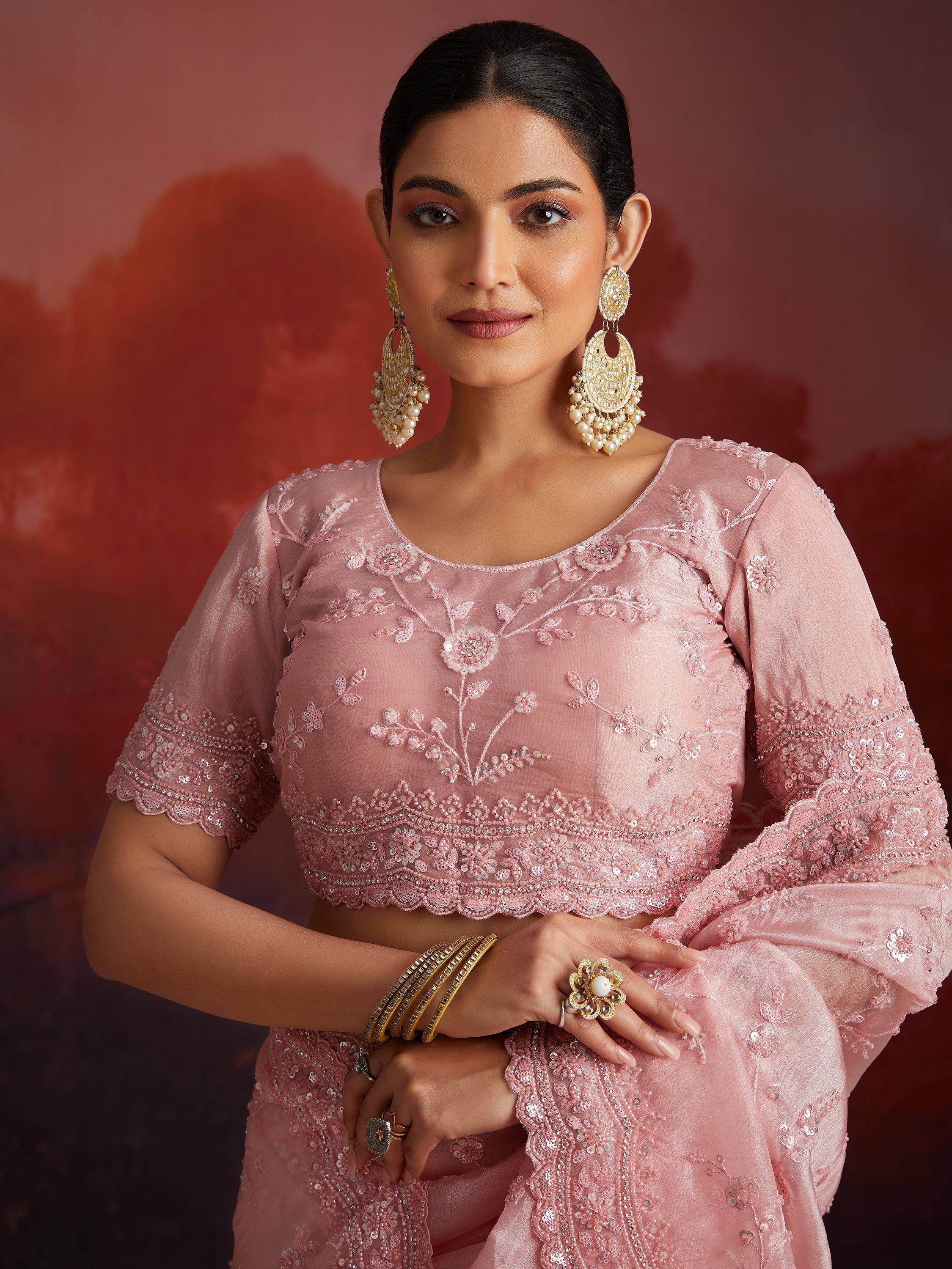 Pink embroidered lehenga choli with floral detailing and gold jewelry, perfect for Indian ethnic wear occasions