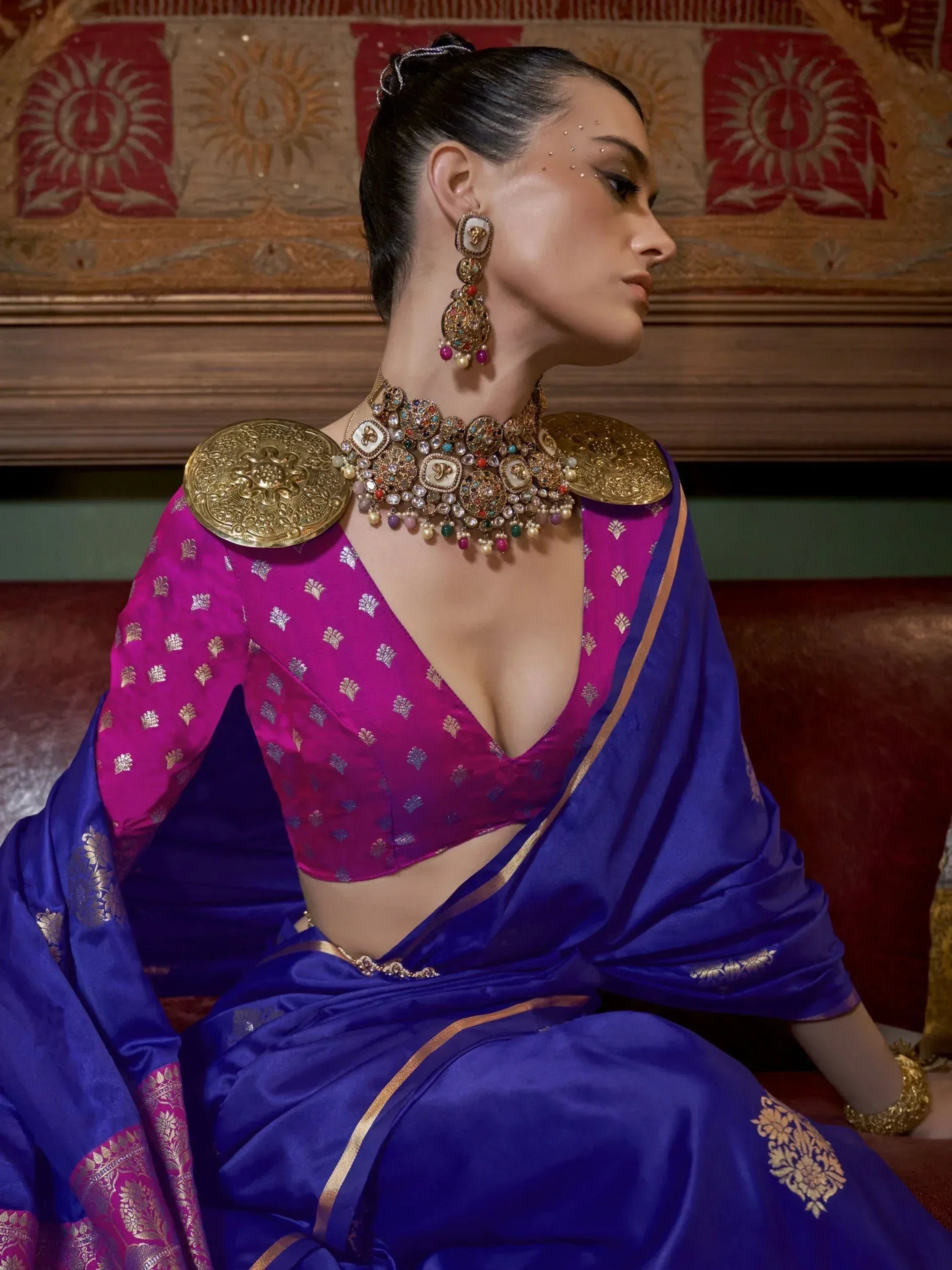 Woman in royal blue saree with magenta blouse, heavy gold jewelry, and traditional Indian ethnic wear