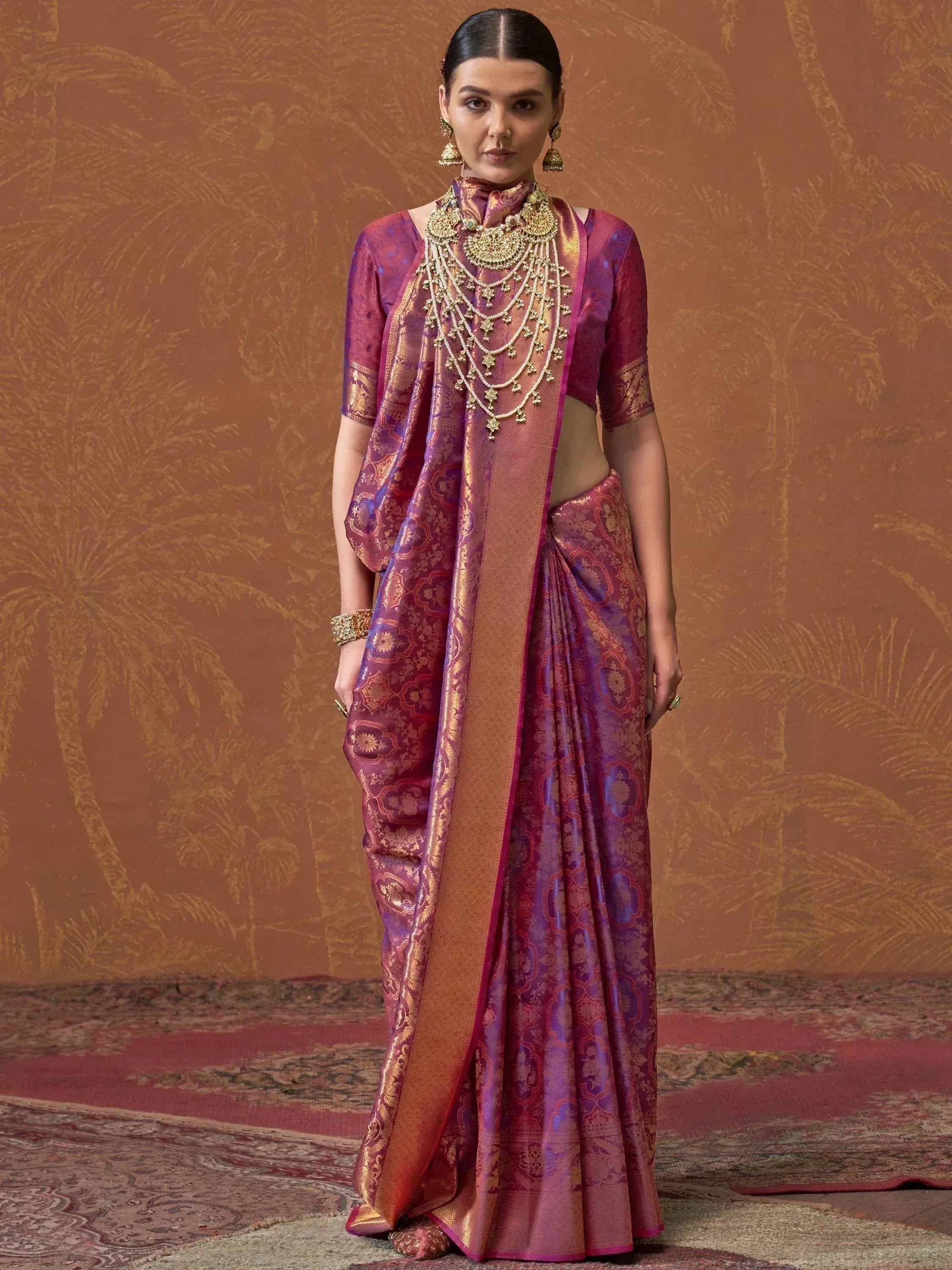 Purple and gold designer saree with intricate embroidery, paired with traditional jewelry for ethnic wear.