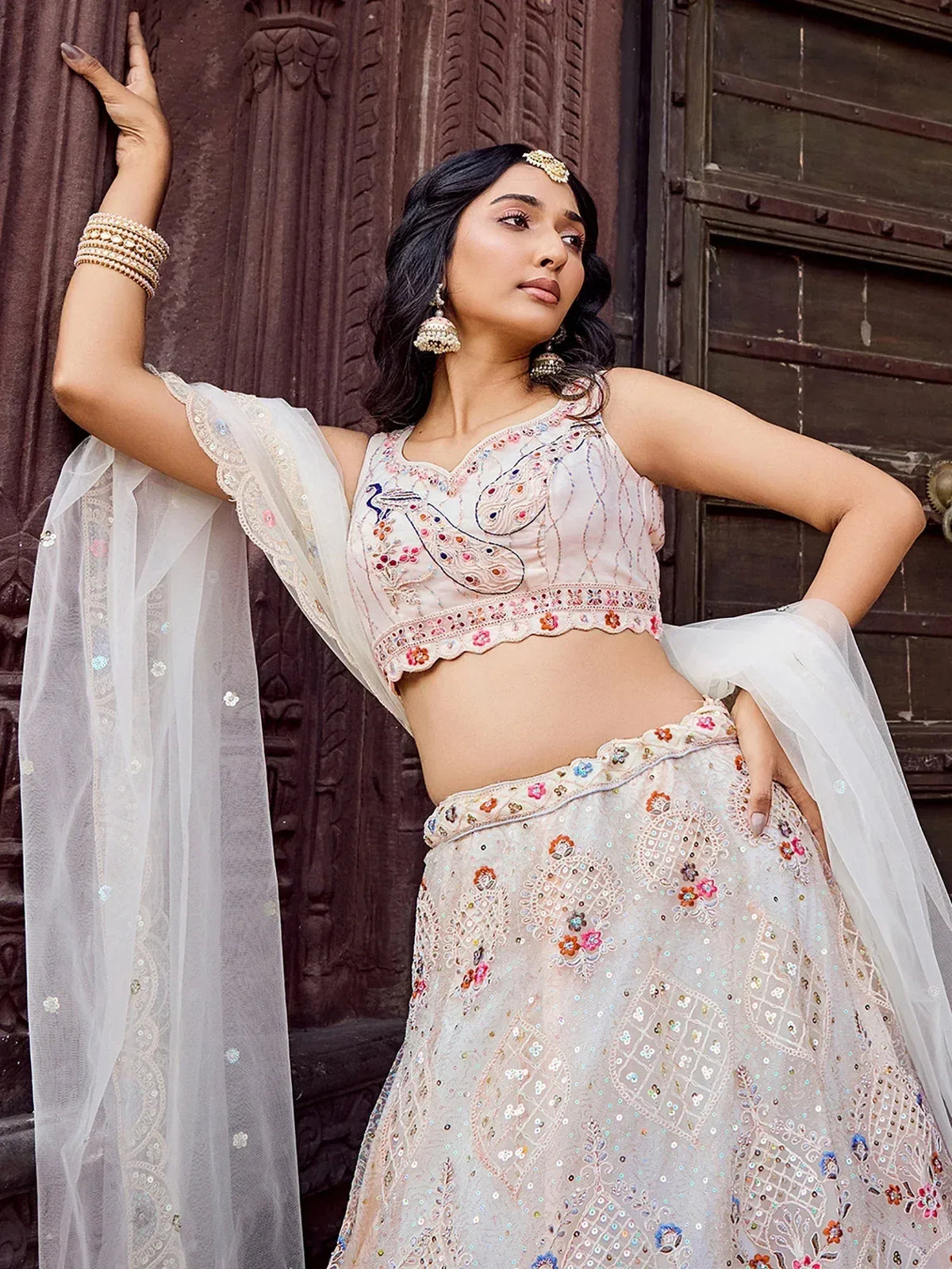 Elegant white embroidered lehenga choli with floral motifs and sheer dupatta, perfect for Indian ethnic wear.