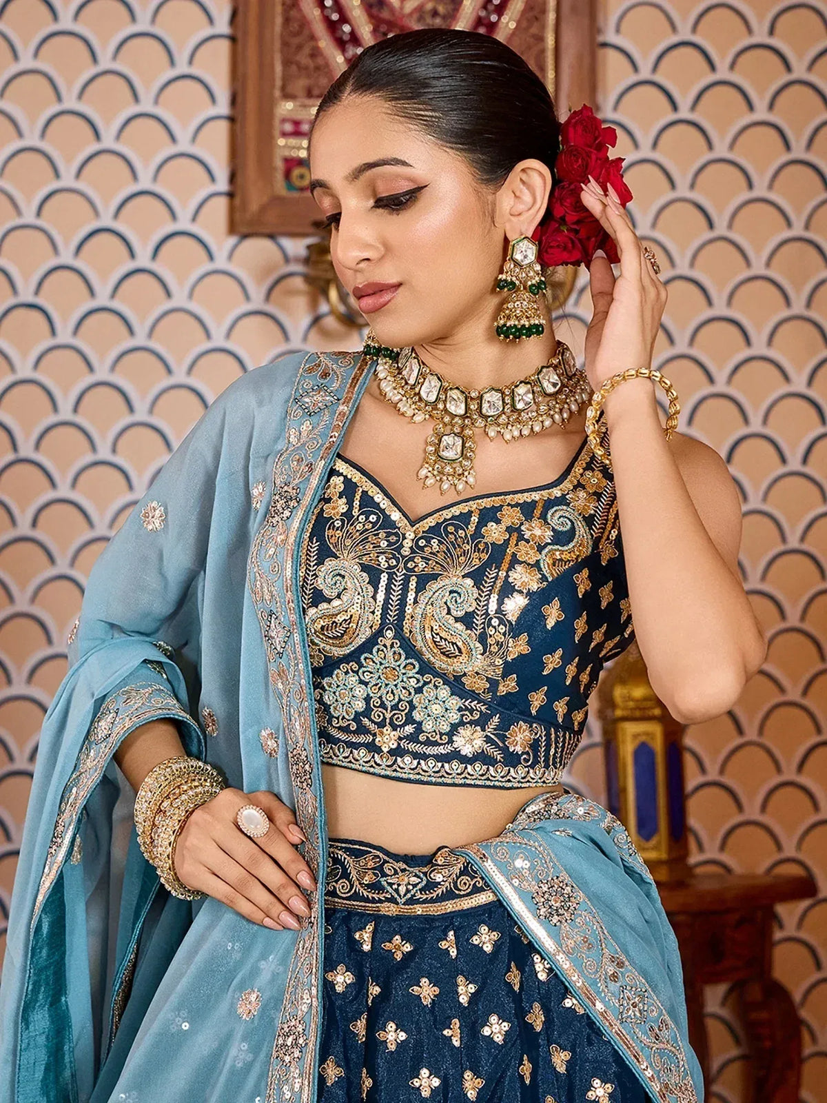 Elegant blue embroidered lehenga choli with gold detailing and matching dupatta, accessorized with traditional jewelry.